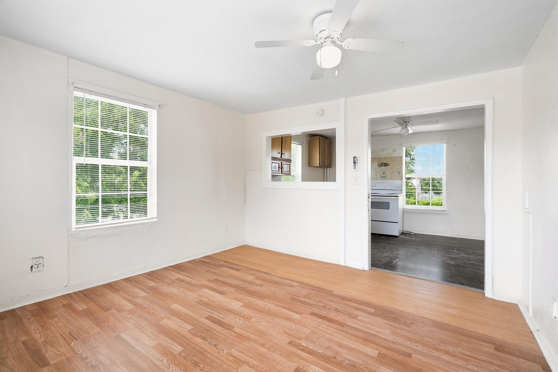 4233 Dupont Street, Houston, TX 77021 The living room offers a comfortable and welcoming space with laminate flooring, a ceiling fan, and windows with privacy blinds, creating the perfect setting for relaxing and entertaining.