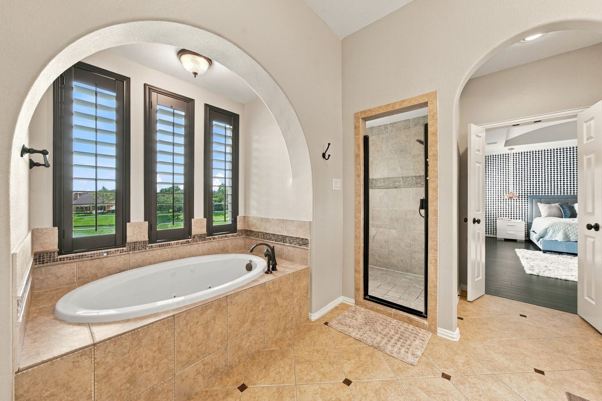 14423 Tivoli Drive, Houston, TX 77077 The spacious primary bathroom includes a jetted soaking tub, separate glass-enclosed shower and tall windows overlooking the lake.