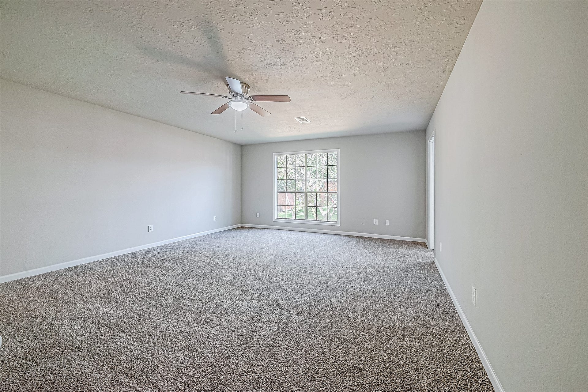 3102 Glenn Lakes Lane, Missouri City, TX 77459 Spacious bedroom with neutral walls, carpeted flooring, large window for natural light, and a ceiling fan.