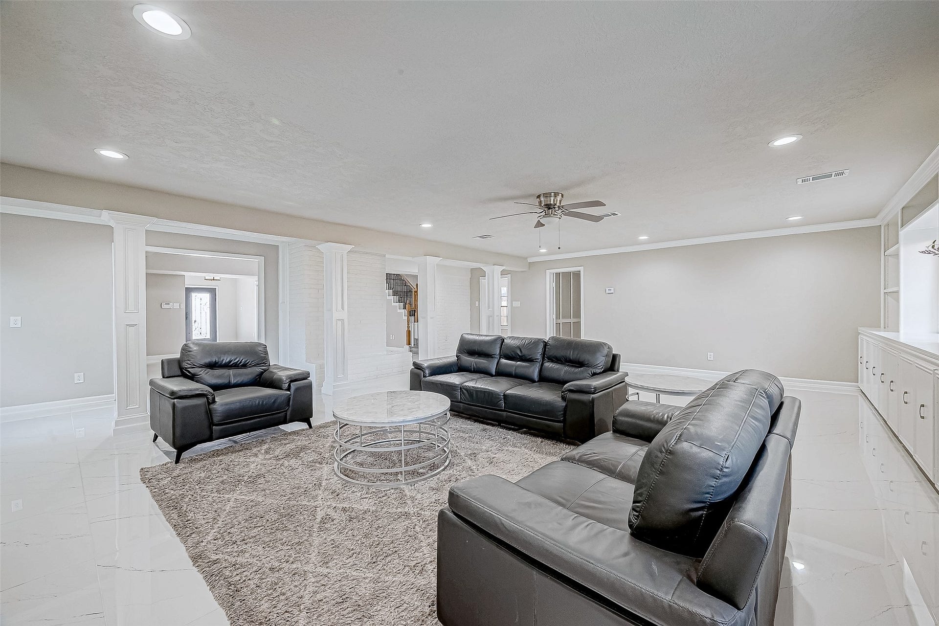 3102 Glenn Lakes Lane, Missouri City, TX 77459 The living room features modern finishes with white tile flooring and recessed lighting.