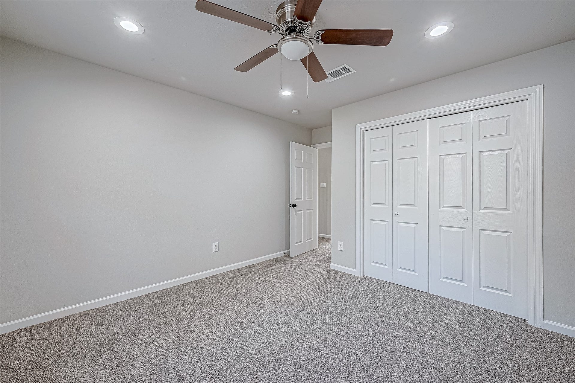 3102 Glenn Lakes Lane, Missouri City, TX 77459 A carpeted bedroom with neutral walls, a ceiling fan, and a double-door closet for ample storage.