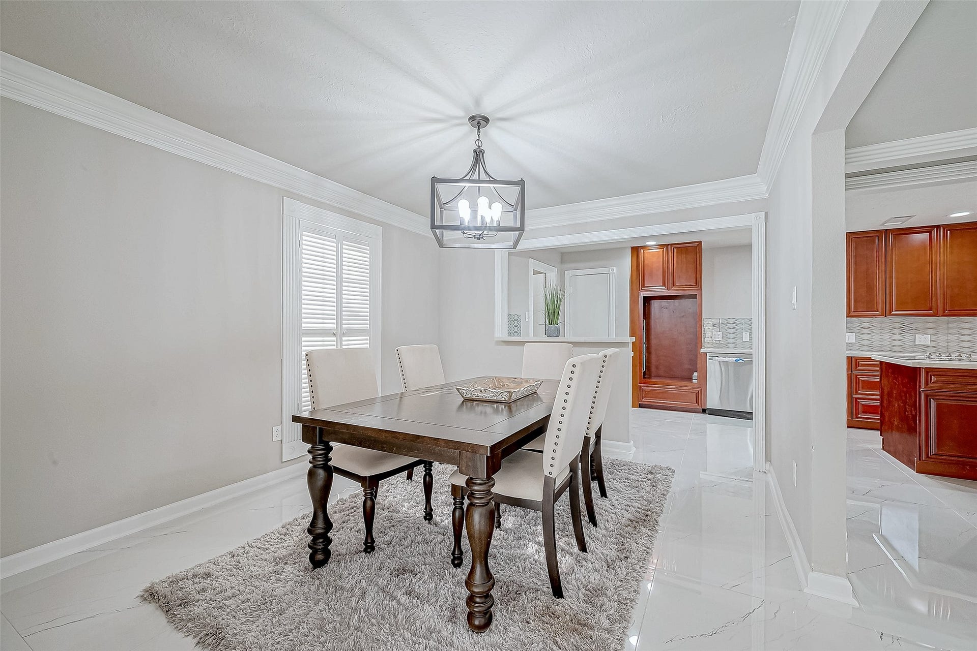 3102 Glenn Lakes Lane, Missouri City, TX 77459 The dining area features elegant crown molding, a chandelier, and neutral tones. It includes a wooden dining table with upholstered chairs.