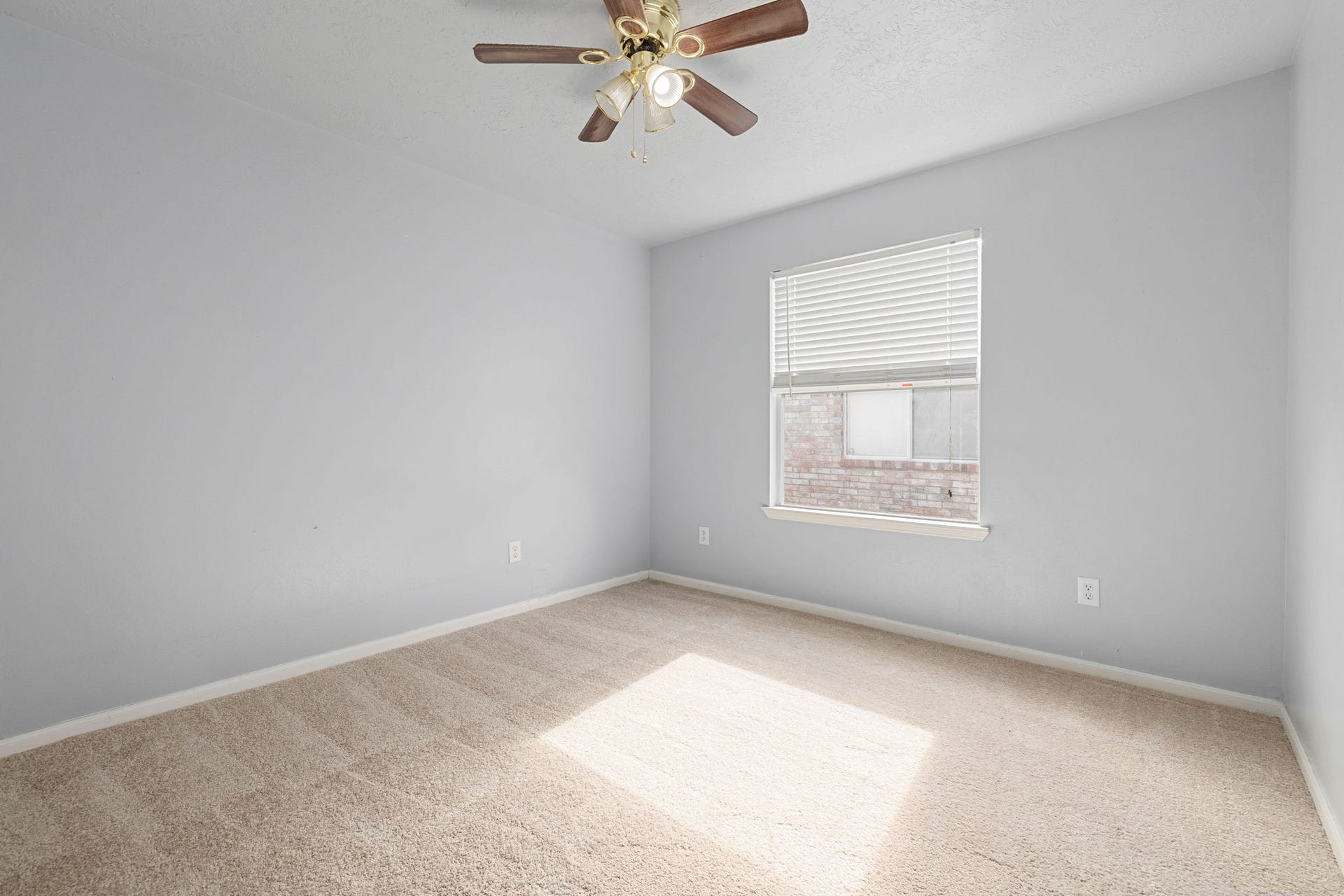 The comfortable bedroom features cozy carpeting, a ceiling fan, and a bright window for natural light.