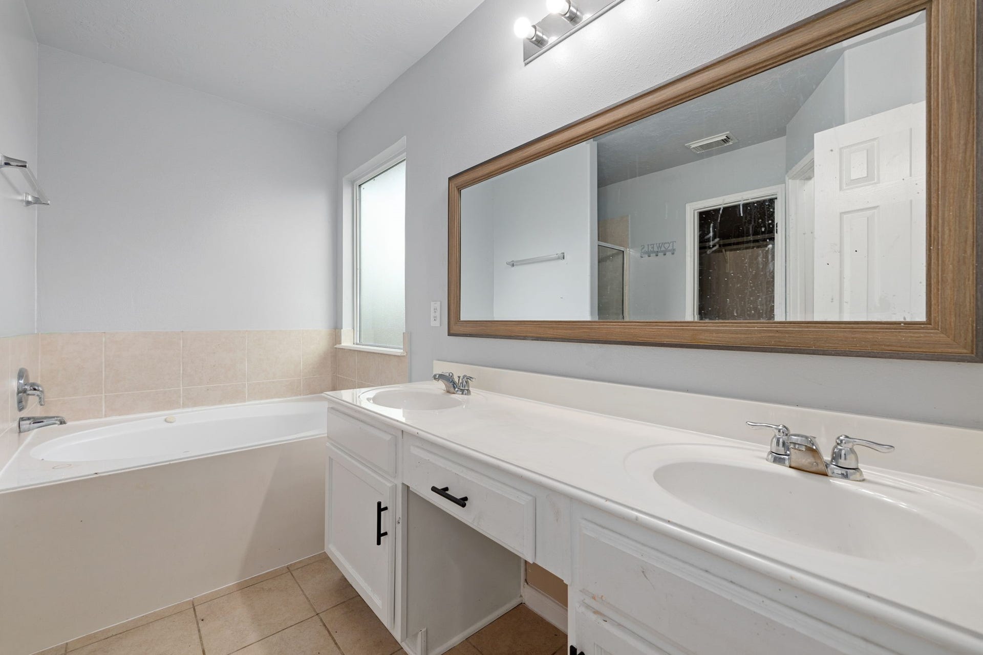 Primary en-suite bath with dual sinks, a soaking tub, separate shower, and walk-in closet.