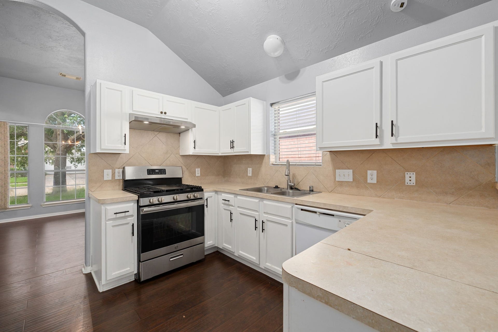 Kitchen featuring white cabinetry, a breakfast bar, gas range, and stainless steel refrigerator.