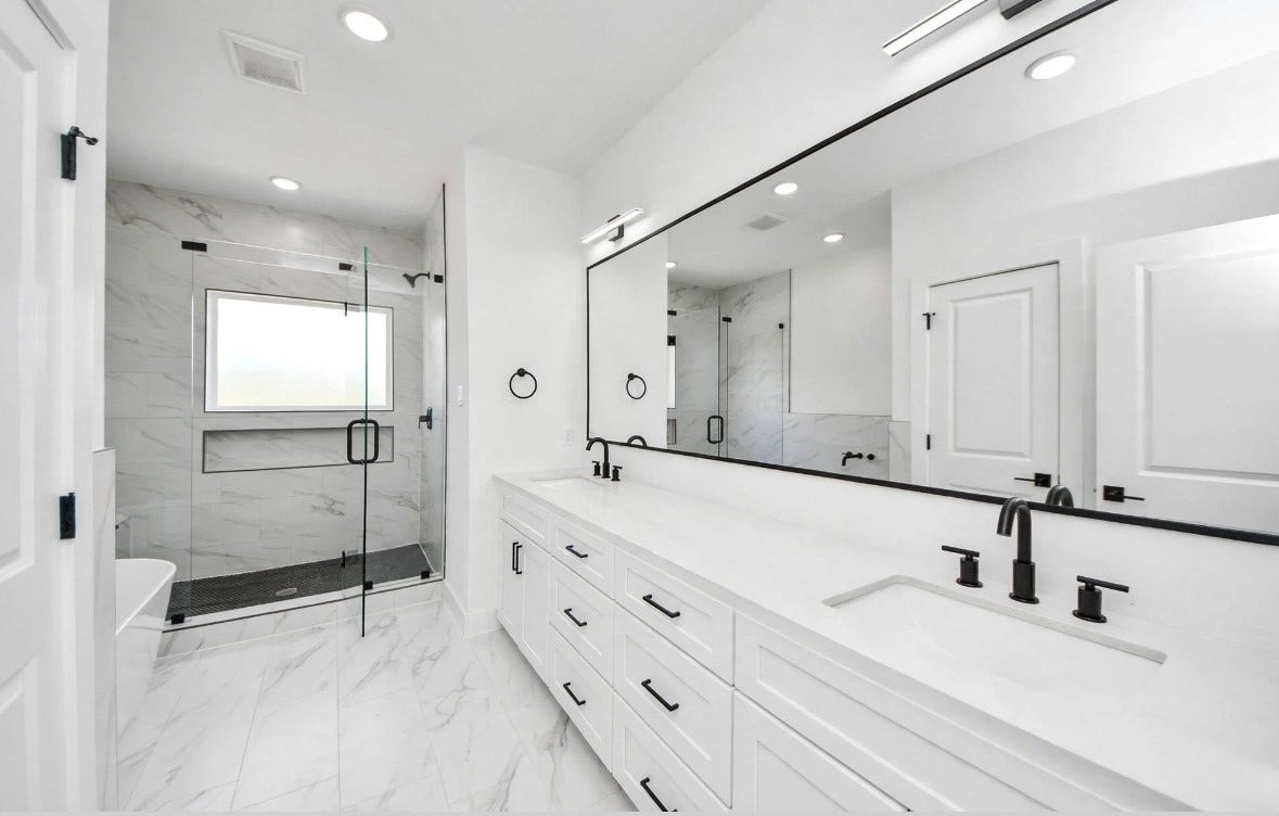 2428 Harrington Street, Houston, TX 77026 Spacious primary bathroom featuring a shower and tub combination with a clean white design and black accents for a sleek, modern finish.