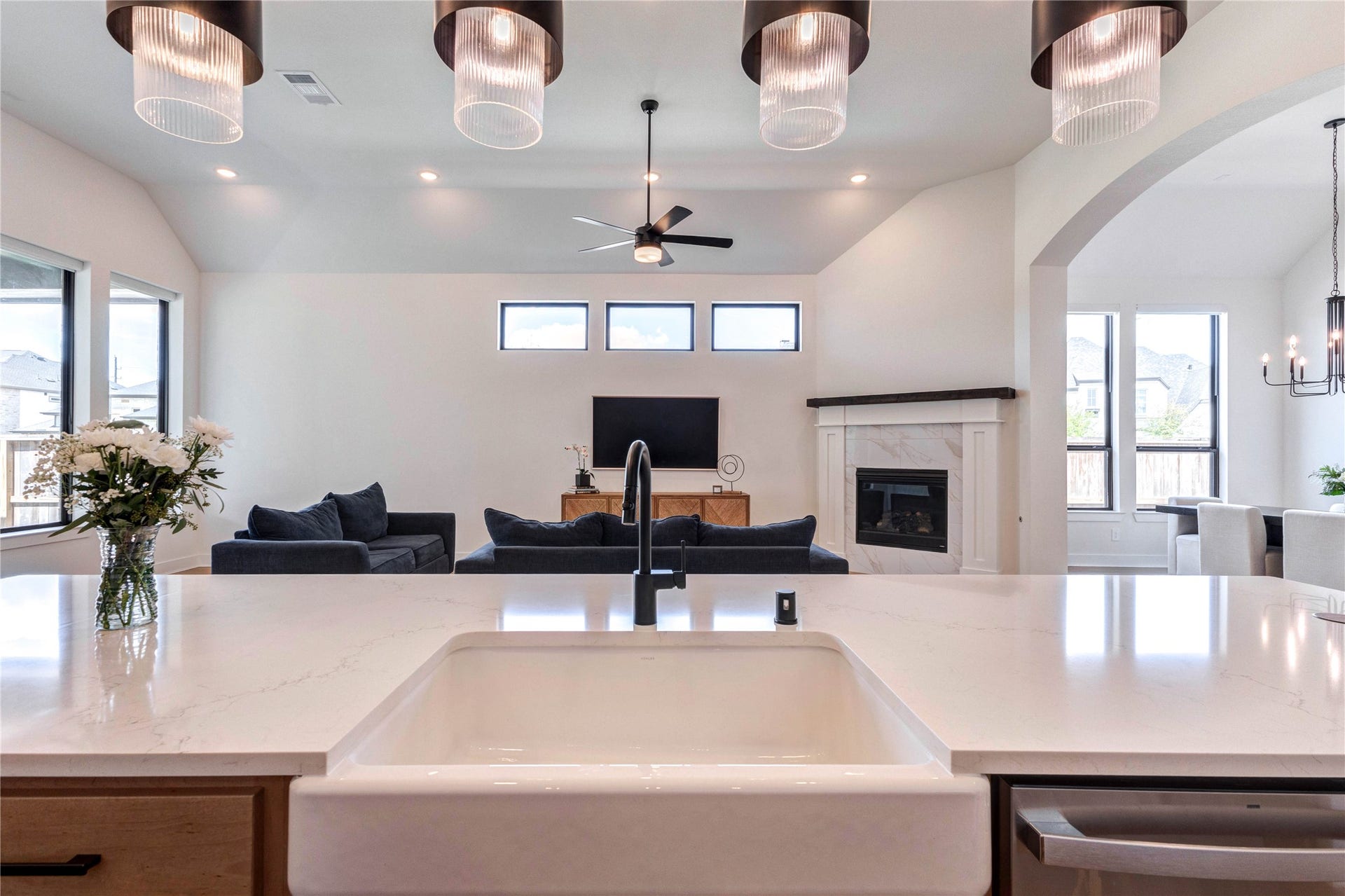 4510 Windmill Landing Lane, Fulshear, TX 77441 This modern kitchen features sleek, dual-tone cabinetry with ample storage, a large island with a farmhouse sink, stainless steel appliances, and elegant pendant lighting. The open layout extends to a dining area with natural light and a stylish chandelier.