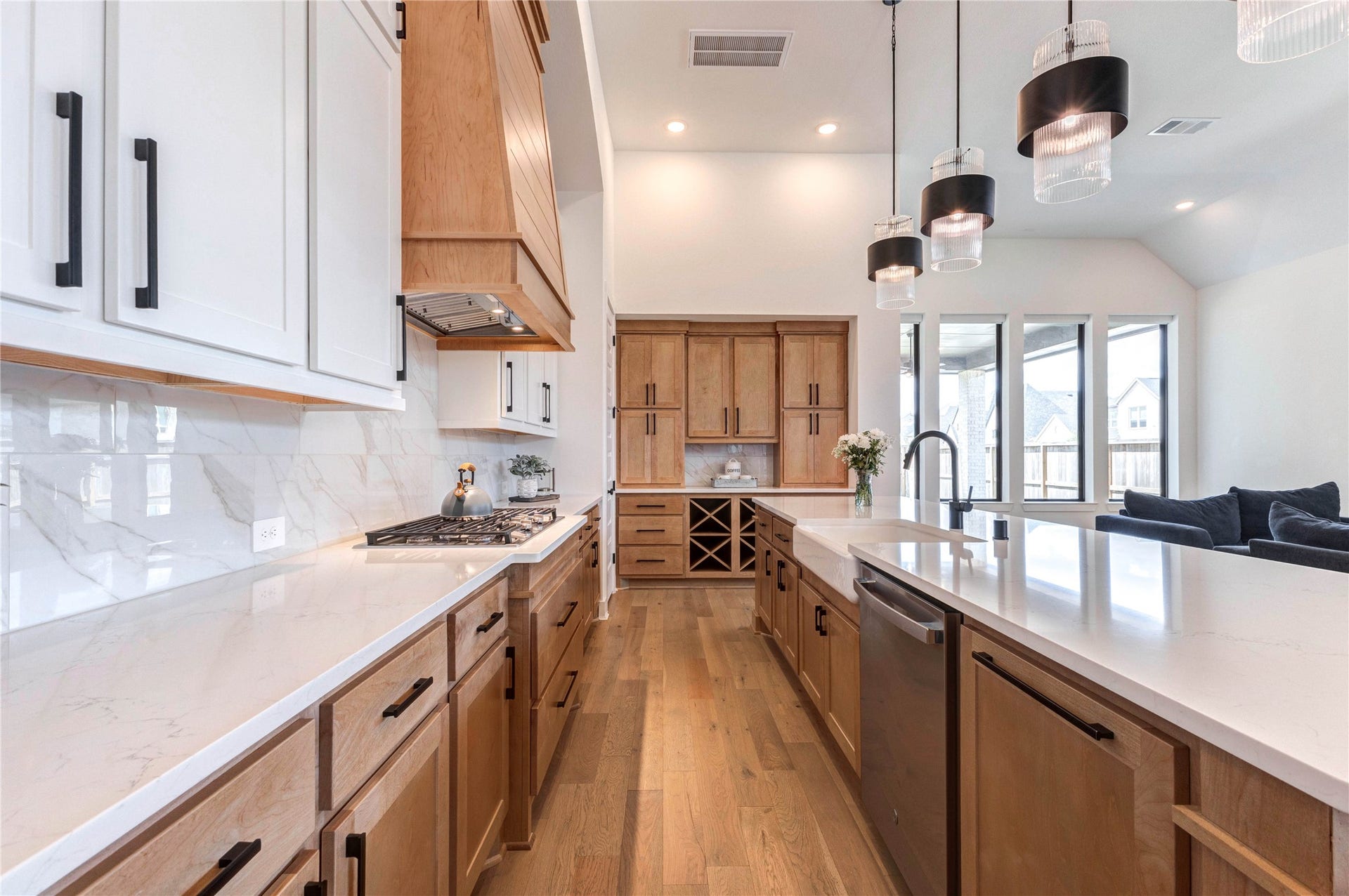4510 Windmill Landing Lane, Fulshear, TX 77441 This open-concept living space features a modern kitchen with an island and pendant lighting, adjacent to a cozy living area with a sleek fireplace and large windows. The room is airy and bright, with hardwood floors and high ceilings.