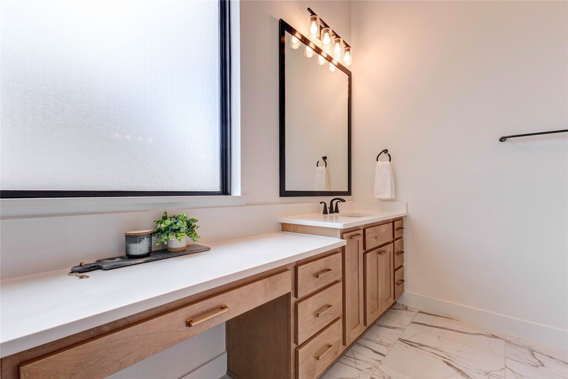 4510 Windmill Landing Lane, Fulshear, TX 77441 This photo features a modern bathroom vanity with a sleek countertop and black fixtures. It has ample storage with wooden cabinets and a large mirror. Adjacent is a spacious walk-in closet with wooden flooring.