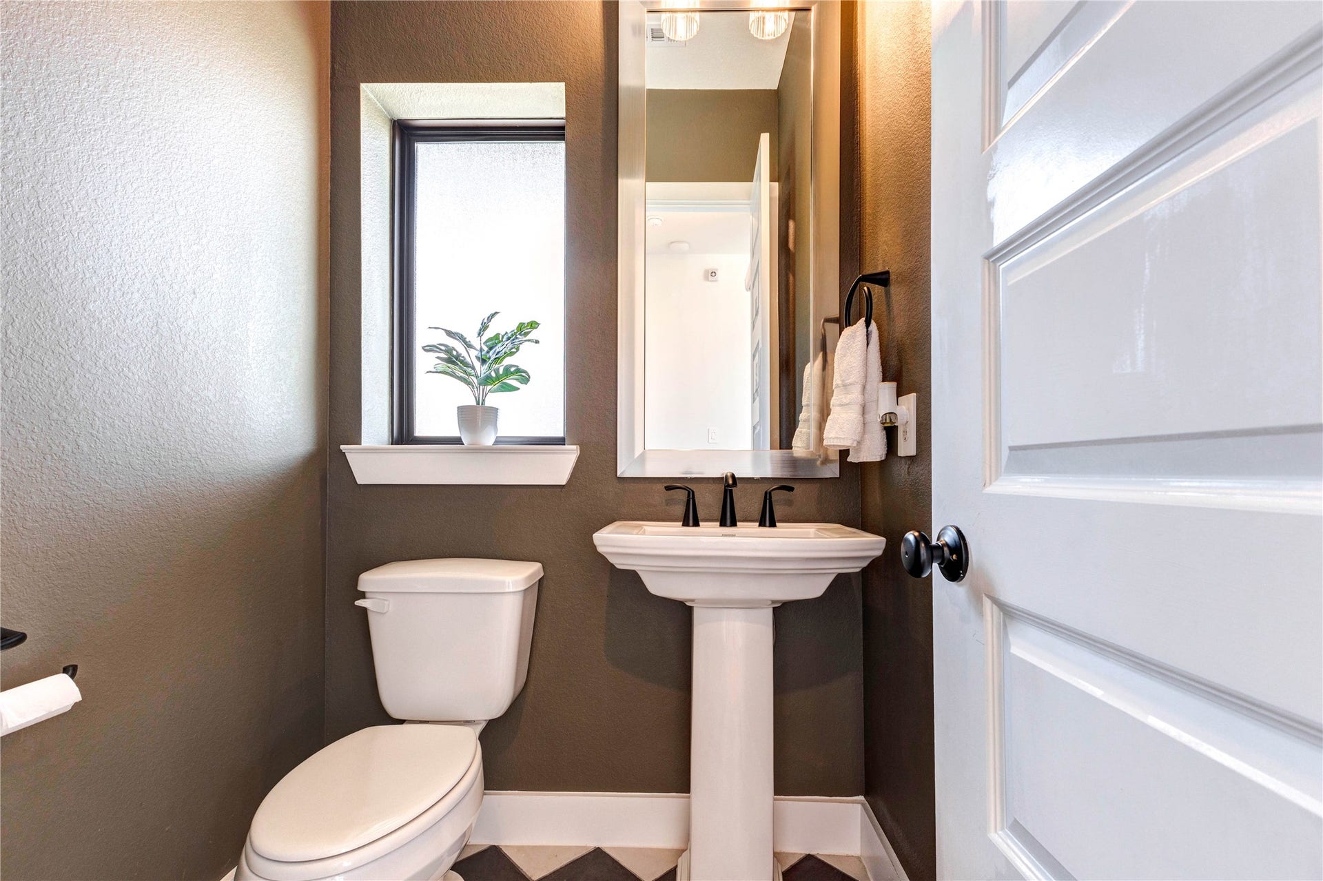 4510 Windmill Landing Lane, Fulshear, TX 77441 Powder room with stylish black-and-white checkered flooring, a matching washer and dryer, and green cabinetry with a sleek countertop. The room connects to a spacious walk-in closet.