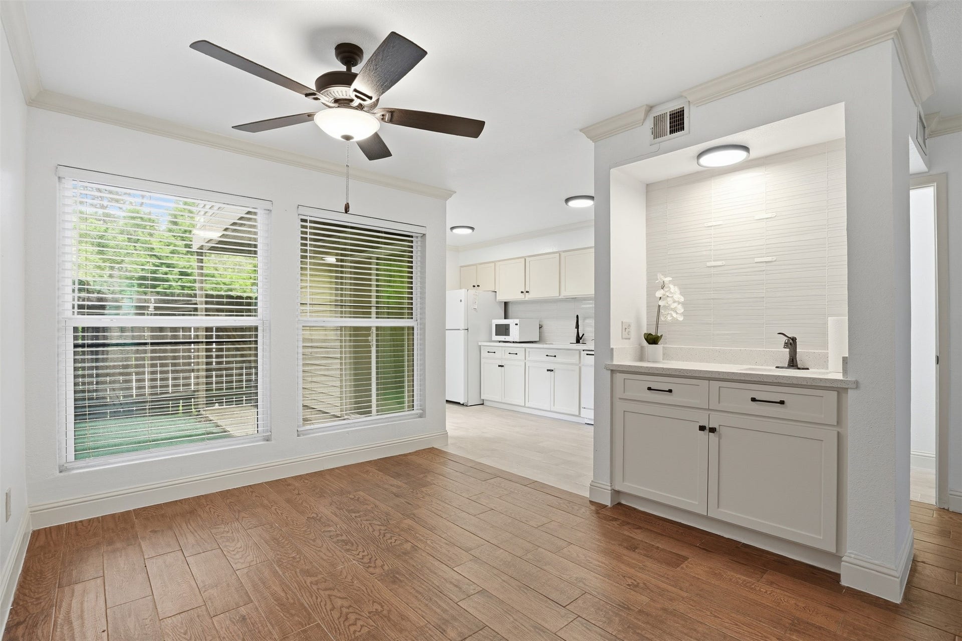 Open dining space with ceiling fan, abundant natural light, beautiful wet bar area and an adjoining kitchen