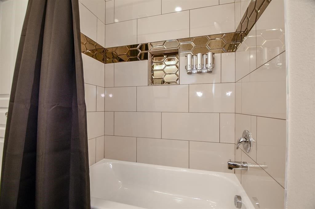 Upstairs Modern bathroom with a sleek bathtub, glossy beige tiles, and stylish hexagonal accent trim.