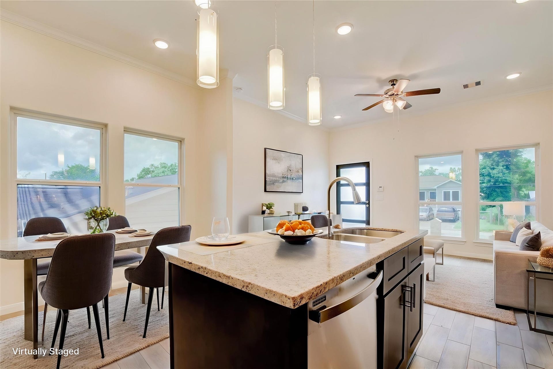This bright, open-concept space features a modern kitchen with an island and granite countertops, flowing into a cozy living area with large windows and stylish dining space. Perfect for entertaining and family gatherings.