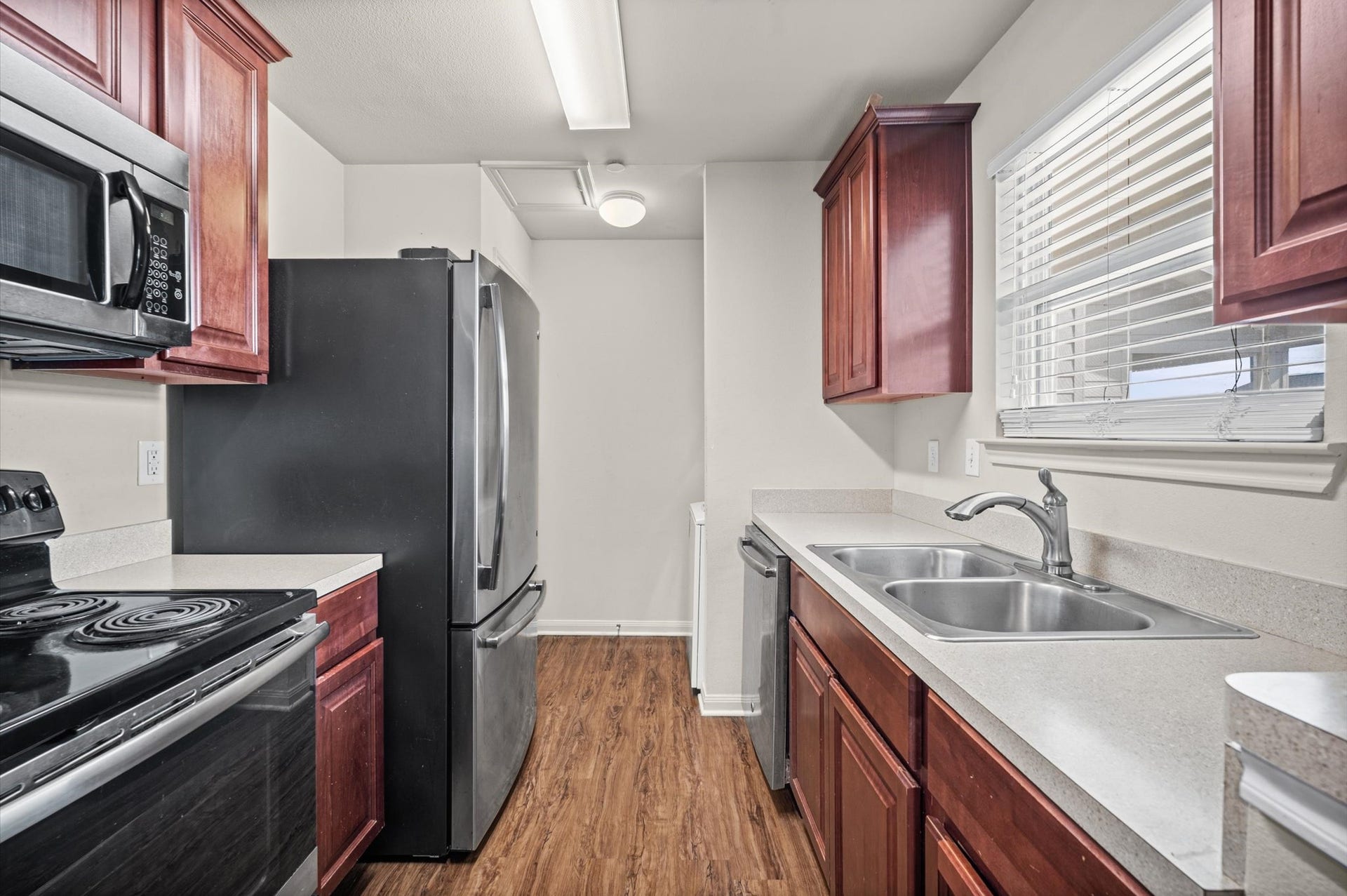 7600 Emmett F Lowry Expressway, #416, Texas City, TX 77591 Charming kitchen with rich wood cabinetry, modern stainless steel appliances, and a bright window overlooking the sink, offering a cozy and functional cooking space.