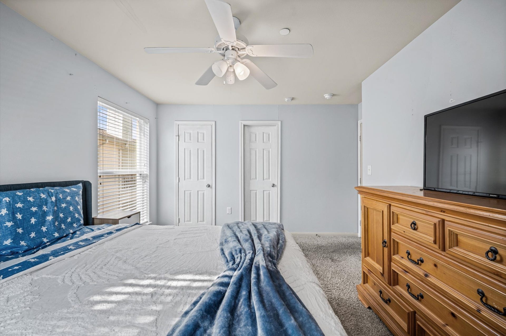 7600 Emmett F Lowry Expressway, #416, Texas City, TX 77591 Cozy bedroom with soft carpeting, a ceiling fan, and abundant natural light from large windows.