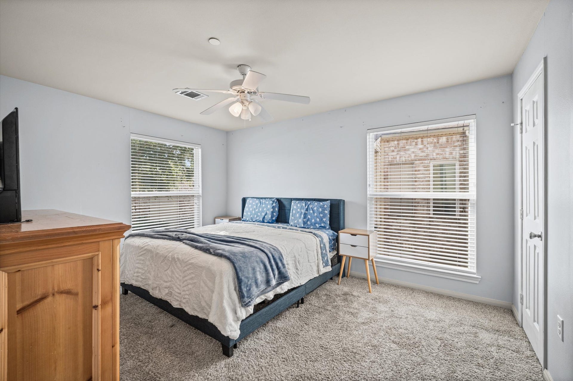7600 Emmett F Lowry Expressway, #416, Texas City, TX 77591 Spacious bedroom with large windows that fill the space with natural light, featuring a cozy carpeted floor and a ceiling fan for added comfort.