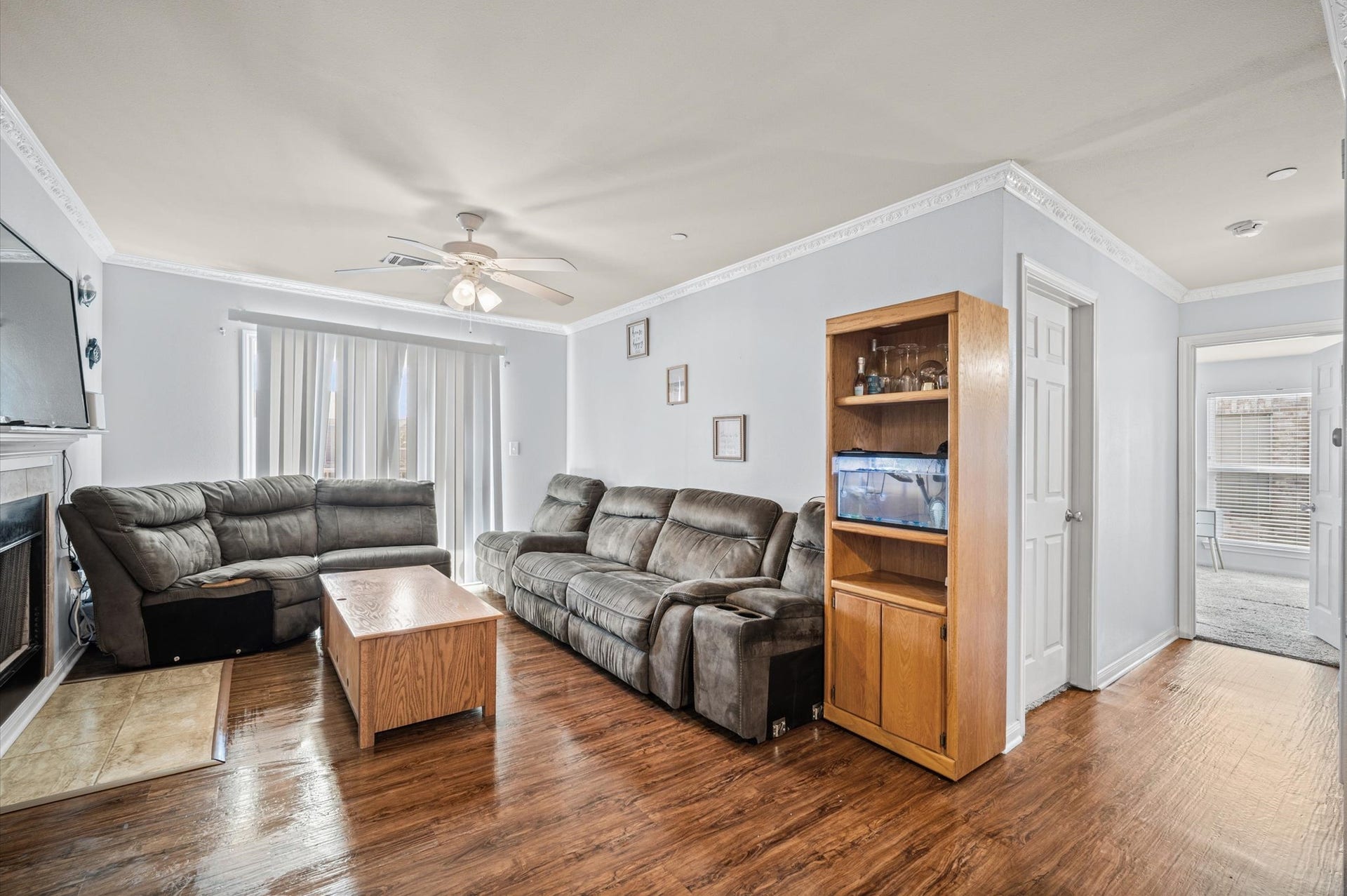 7600 Emmett F Lowry Expressway, #416, Texas City, TX 77591 Spacious living room with hardwood floors, cozy living space, and a ceiling fan for comfort. Natural light fills the room through large sliding doors, and a charming fireplace adds warmth and ambiance.