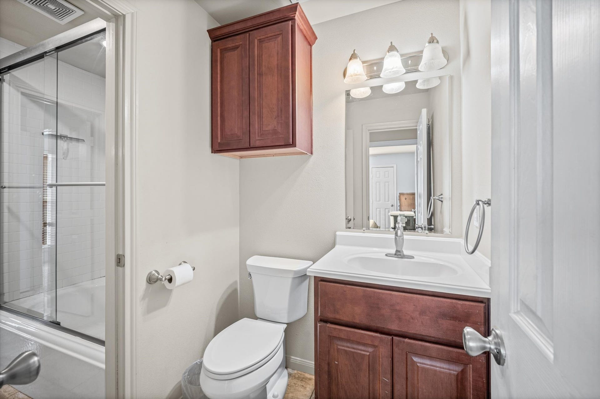 7600 Emmett F Lowry Expressway, #416, Texas City, TX 77591 Charming bathroom featuring a sleek glass-enclosed shower, elegant vanity with ample storage, and warm wooden cabinetry.
