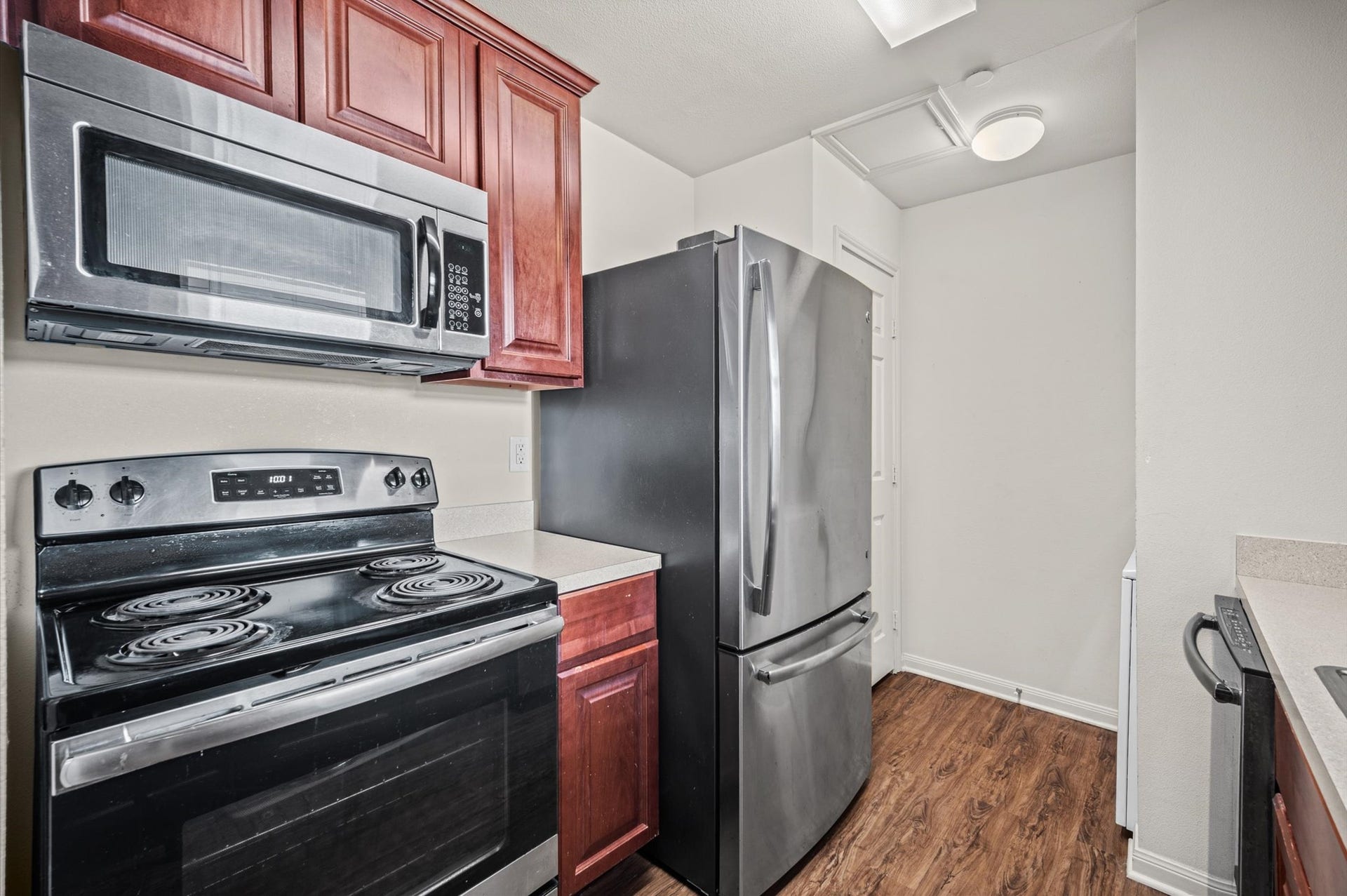 7600 Emmett F Lowry Expressway, #416, Texas City, TX 77591 Modern kitchen featuring sleek stainless steel appliances, rich wooden cabinetry, and elegant countertops, all set upon warm wood laminate flooring.