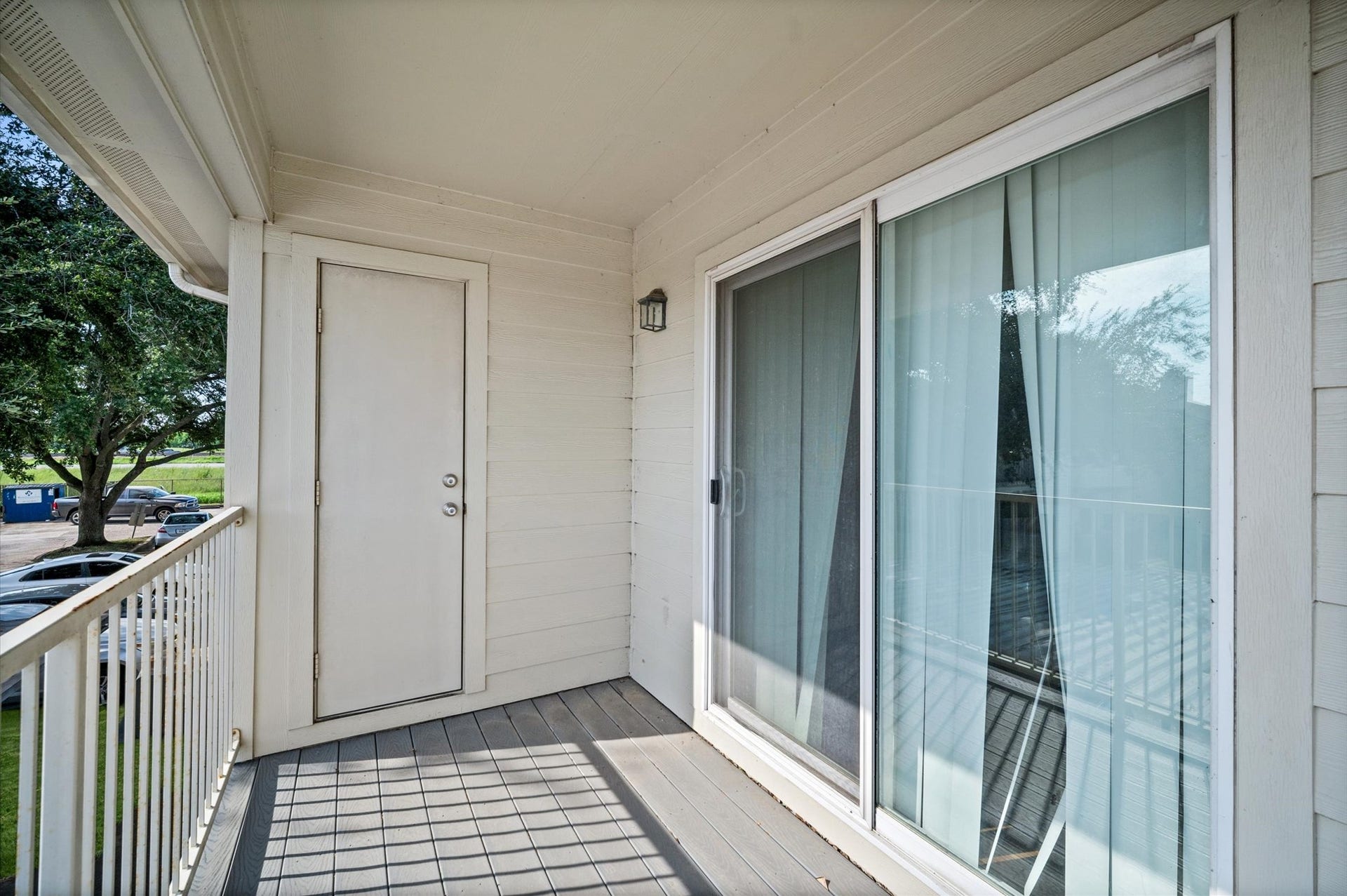 7600 Emmett F Lowry Expressway, #416, Texas City, TX 77591 Charming balcony with sliding glass doors, offering a cozy outdoor space and a view of lush greenery.