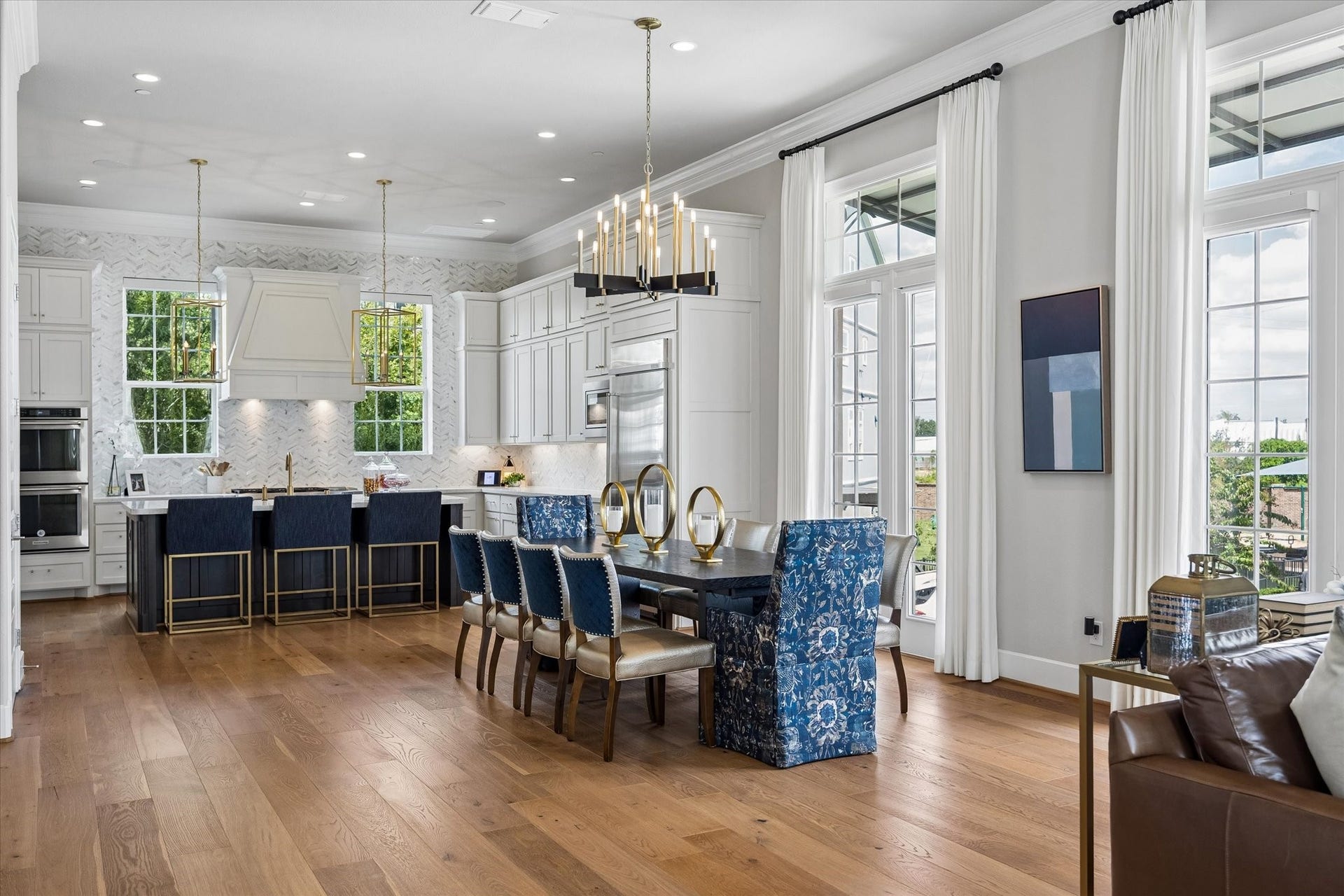 The dining area is a true centerpiece, anchored by a custom chandelier and framed by double-stacked windows that fill the space with light. Its seamless flow into the kitchen makes the layout perfect for entertaining.