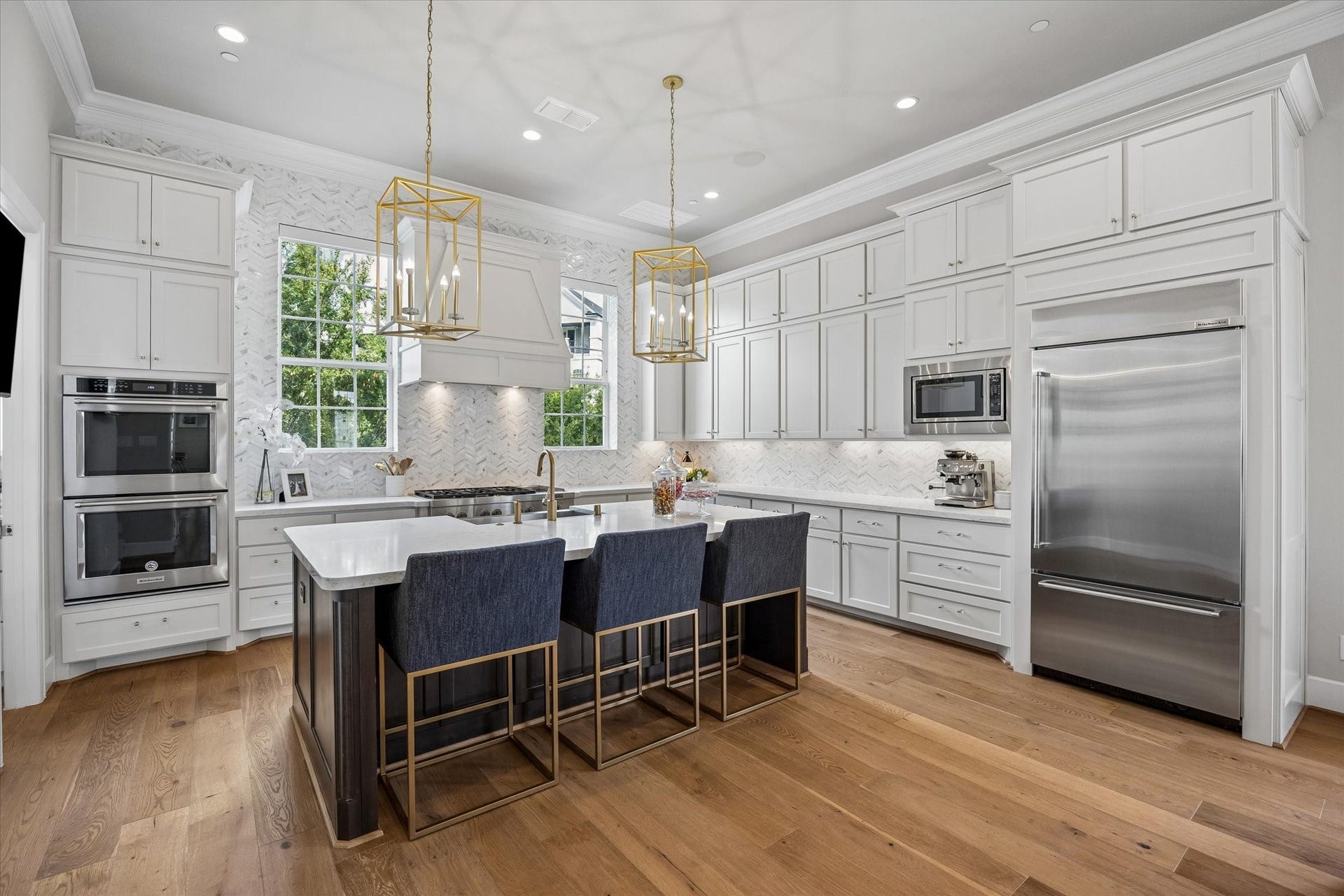 This incredible kitchen is a chefs dream, anchored by a massive Quartz island and premium appliances including Jenn-Air 6-burner commercial-grade cooktop and Kitchenaid double ovens. High-end finishes like herringbone tile backsplash and soft-close cabinetry pair perfectly with a custom pantry featuring thoughtful built-ins.