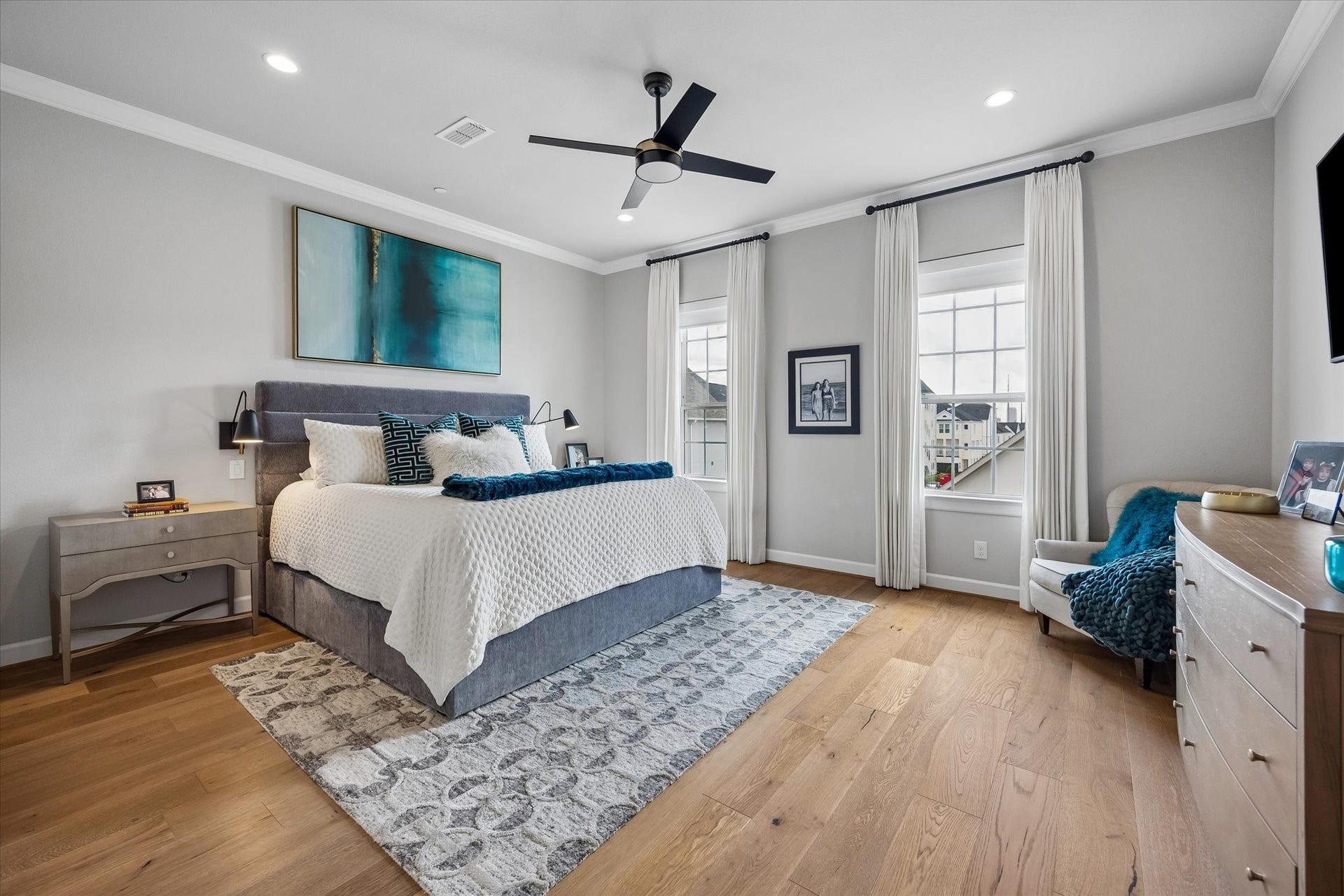 The primary suite is a sophisticated retreat featuring rich wood floors, crown molding, and a sun-filled sitting area. High-end Hunter Douglas shades offer light control, while the custom walk-in closet provides tailored organization for a streamlined lifestyle.