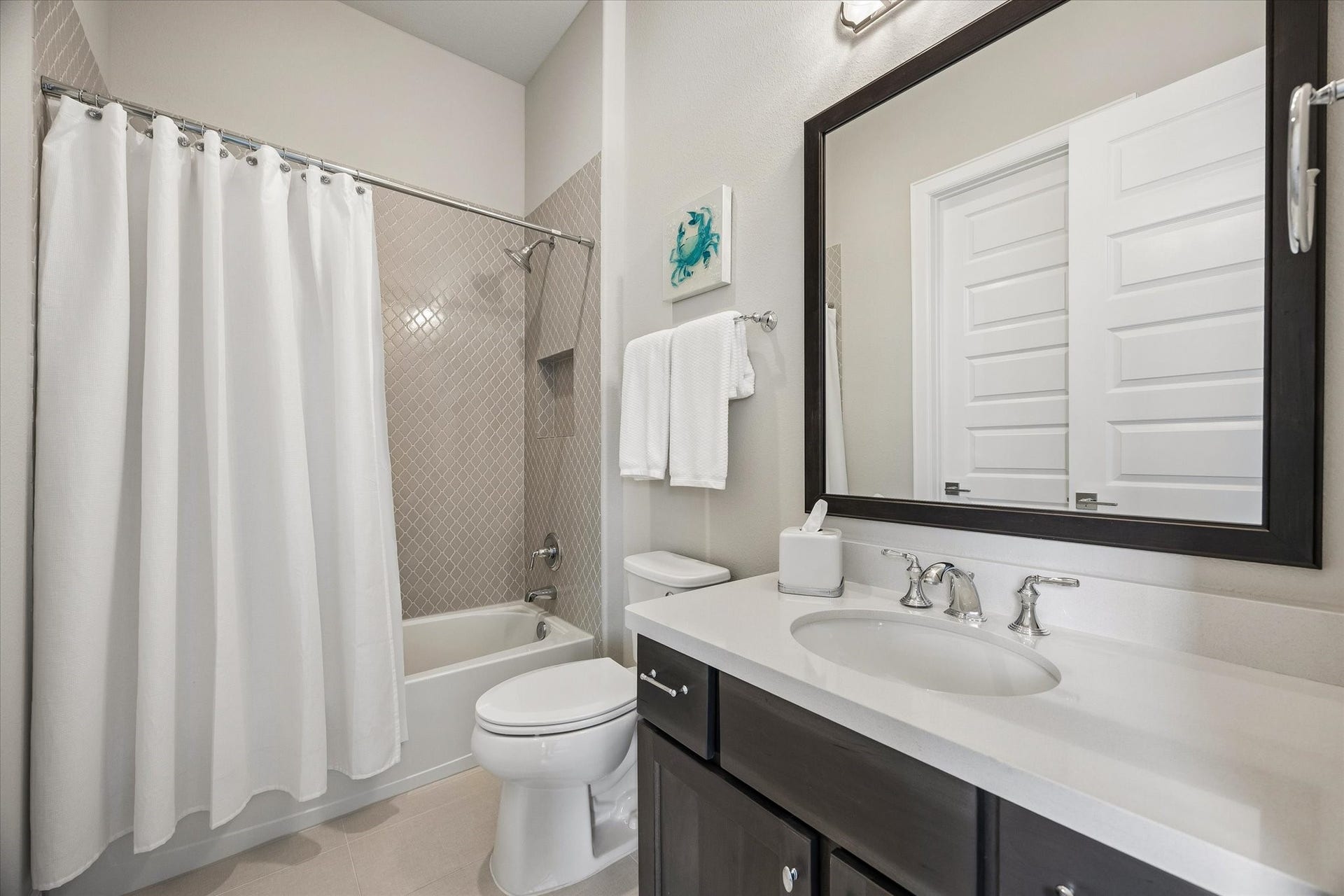 The ensuite bathroom serves as a refined retreat, featuring elegant Quartz countertops and a tub-shower combination accented by tasteful beveled wall tile and a built-in toiletry shelf.
