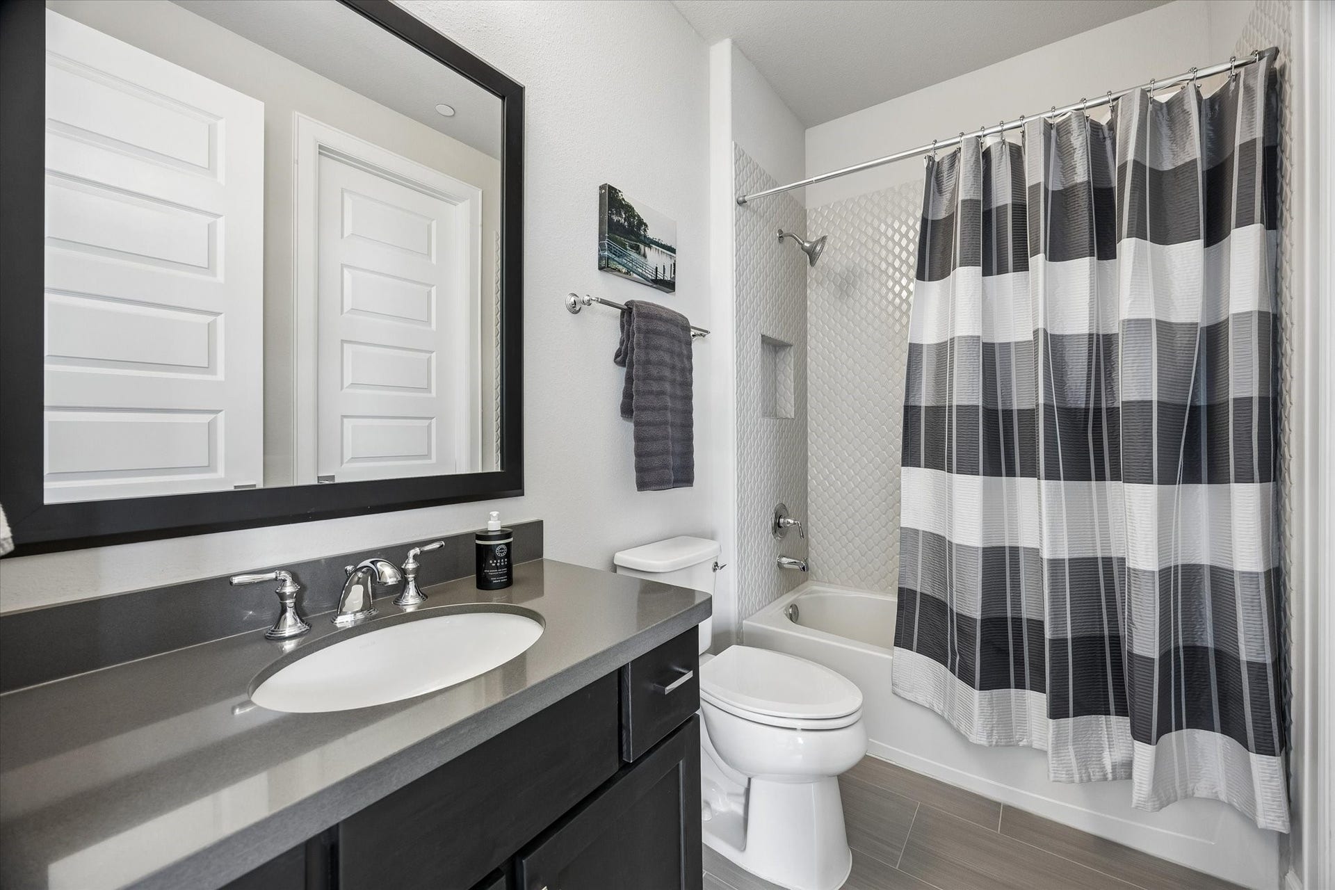 Ensuite bath features elegant Quartz countertops and a tub-shower combo framed by stunning designer tile surround.