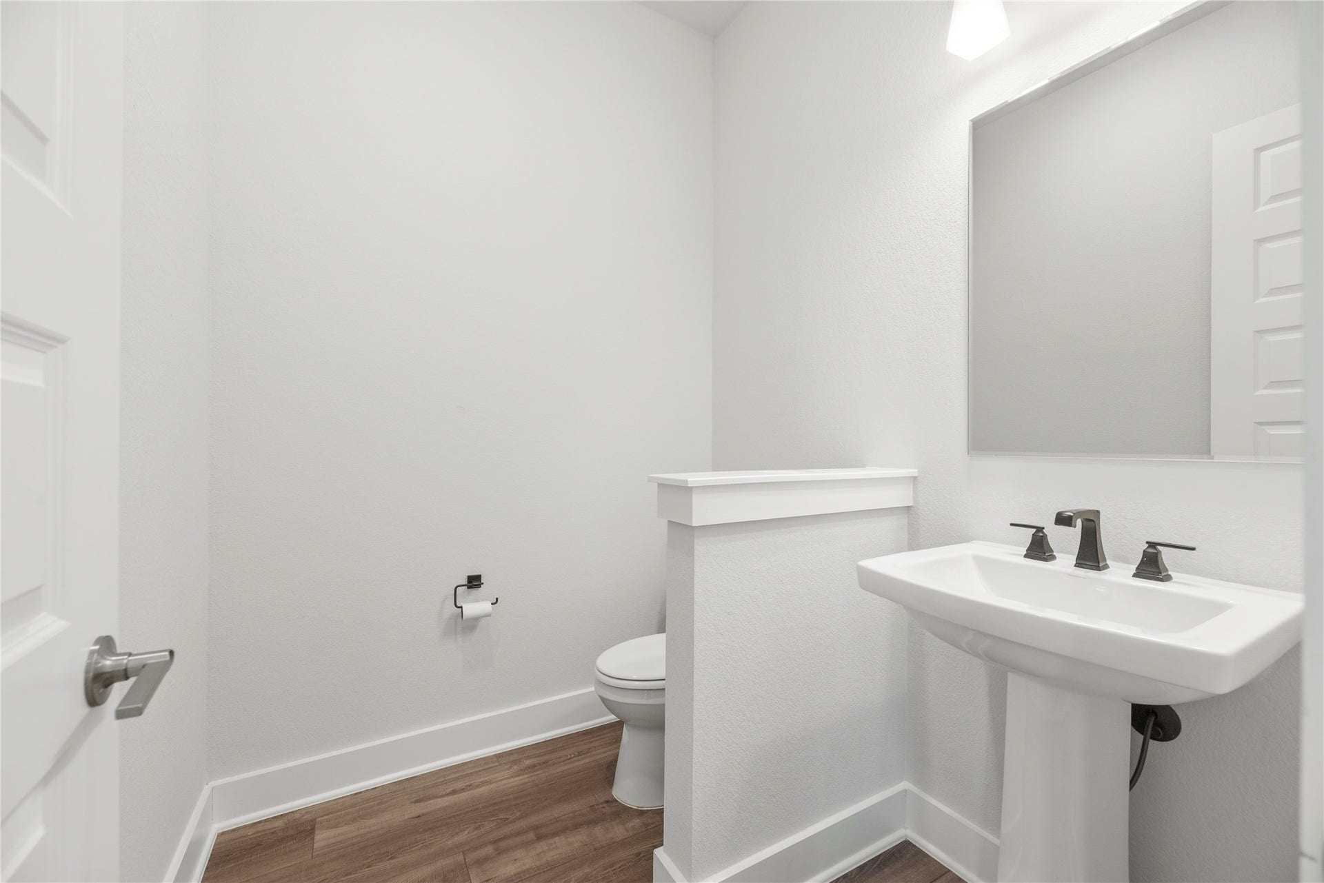 10314 Forest Lake Drive, Missouri City, TX 77459 Convenient guest half bath complete with a classic pedestal sink, modern dark bronze fixtures, framed mirror, and privacy half-wall.