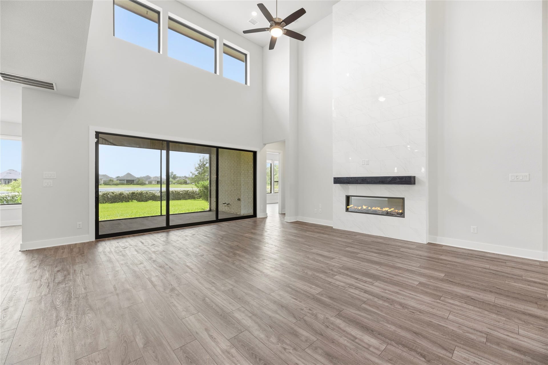 10314 Forest Lake Drive, Missouri City, TX 77459 Focal point living room featuring a dramatic floor-to-ceiling tiled gas fireplace with mantel, two-story upper transoms, and sliding glass doors leading to the covered back porch.