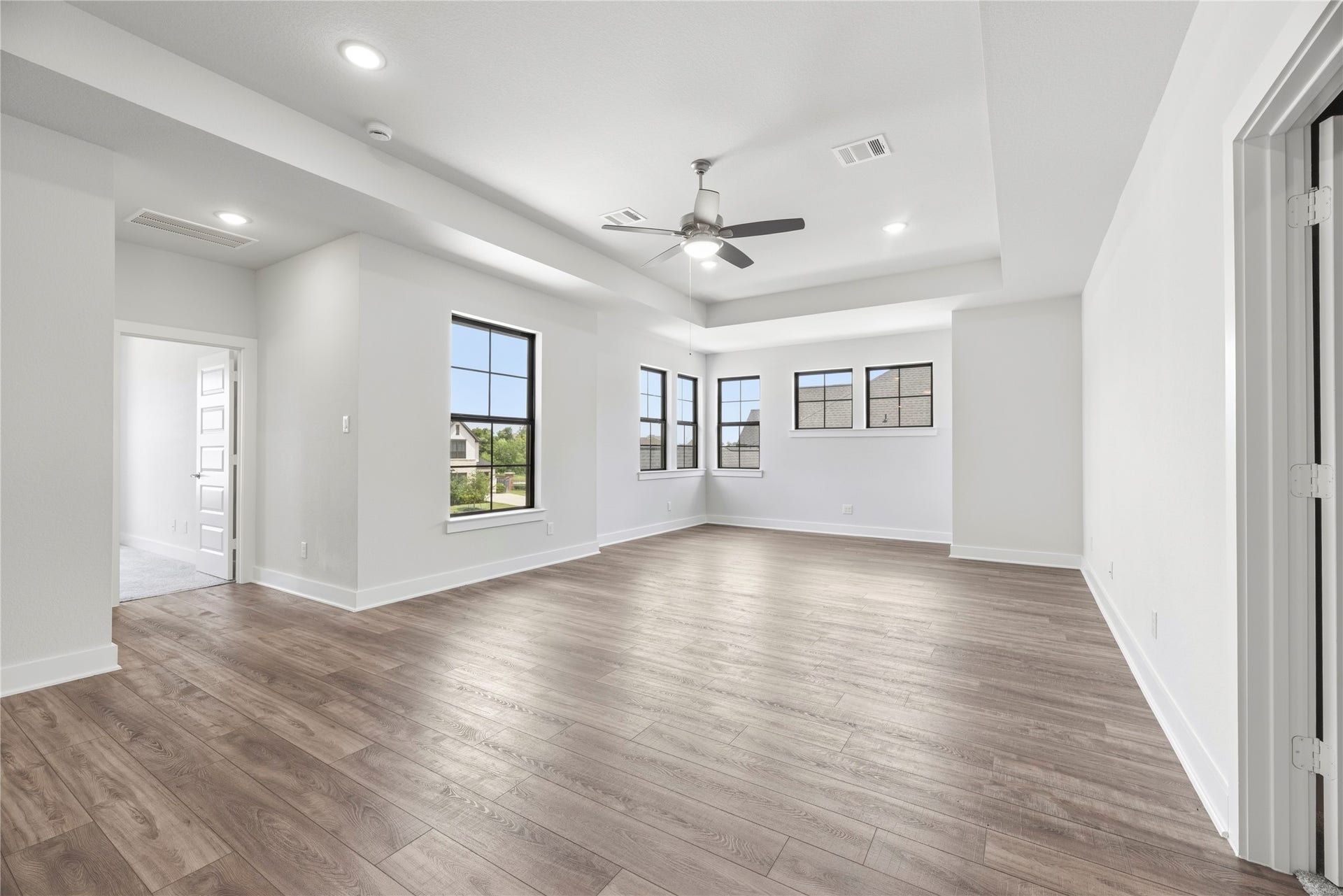 10314 Forest Lake Drive, Missouri City, TX 77459 Generous game room featuring tray ceilings, wood-look flooring, and custom built-in white shelving along the rear wall.