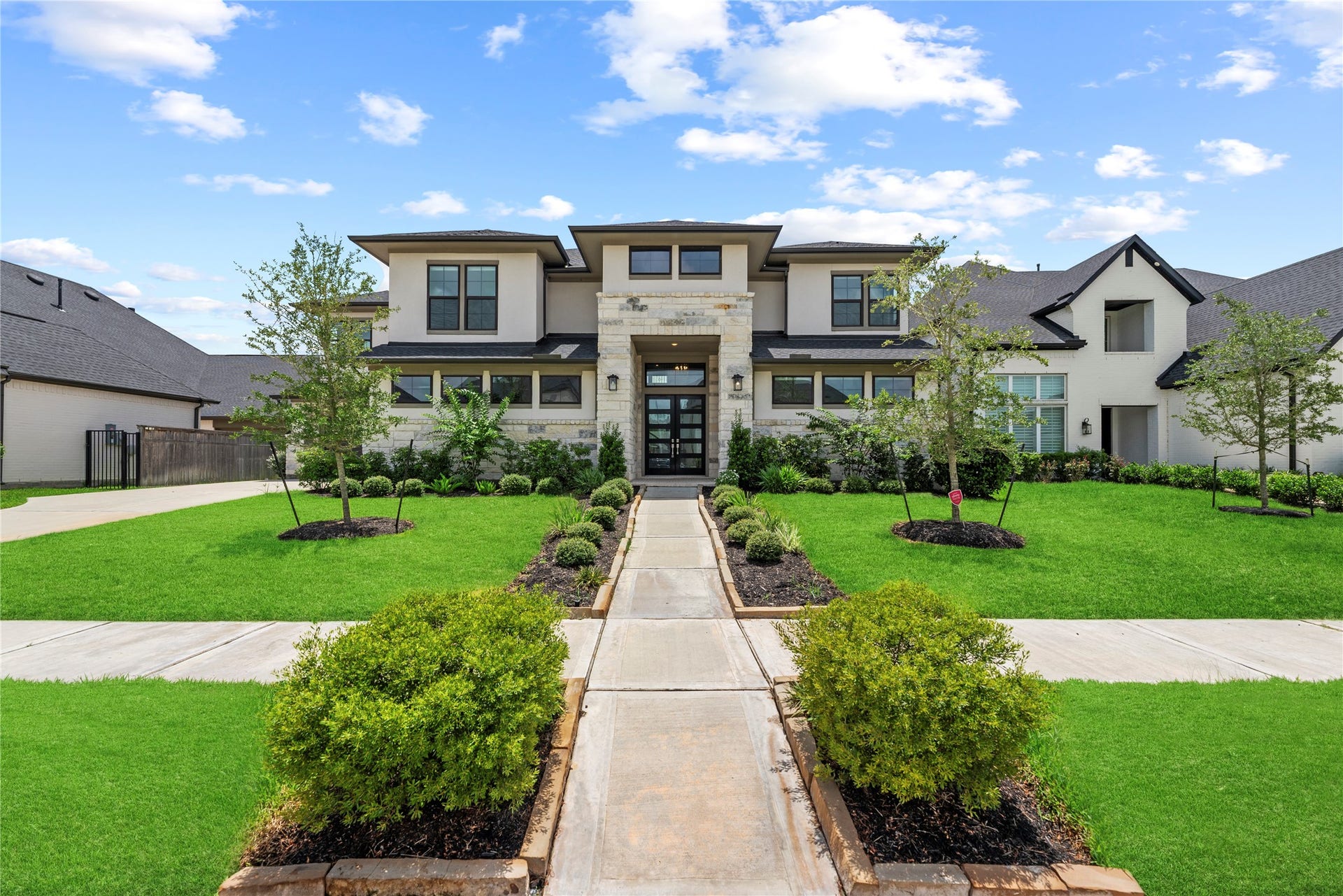 10314 Forest Lake Drive, Missouri City, TX 77459 Impressive curb appeal featuring modern double front doors, stone accent pillar entrance, and pristine professional landscaping under clear blue skies.