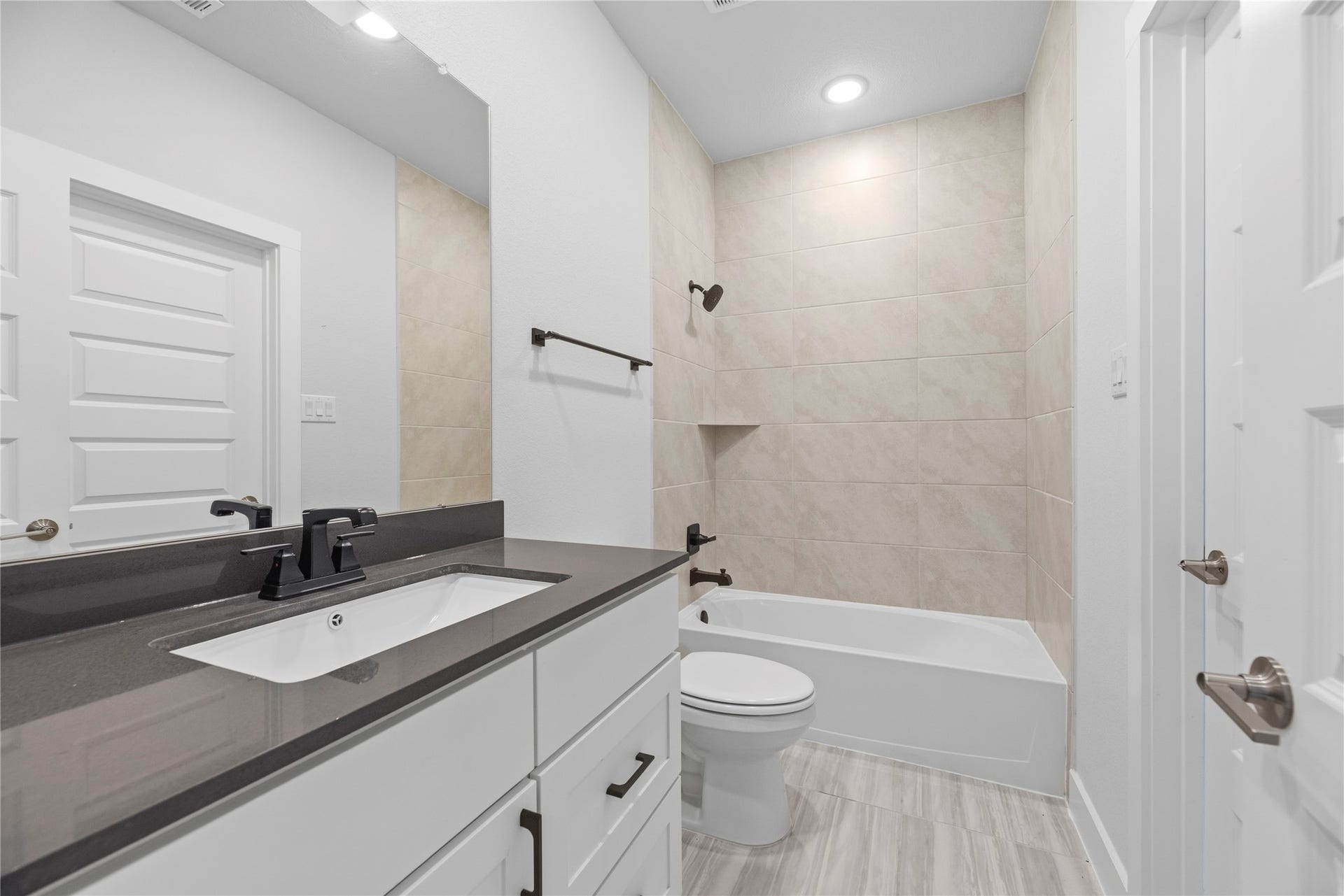 10314 Forest Lake Drive, Missouri City, TX 77459 Well-appointed bathroom equipped with a dark quartz vanity, white cabinetry, matte black hardware, and a tiled tub/shower combination.