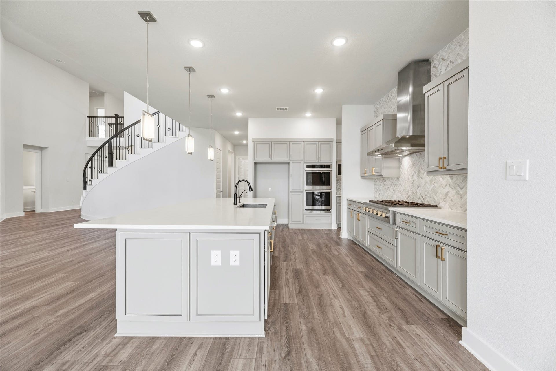 10314 Forest Lake Drive, Missouri City, TX 77459 Angle showcasing the clean sightlines, abundant drawer and cabinet storage, gold/brass pull accents, built-in double ovens, and nearby grand foyer view.