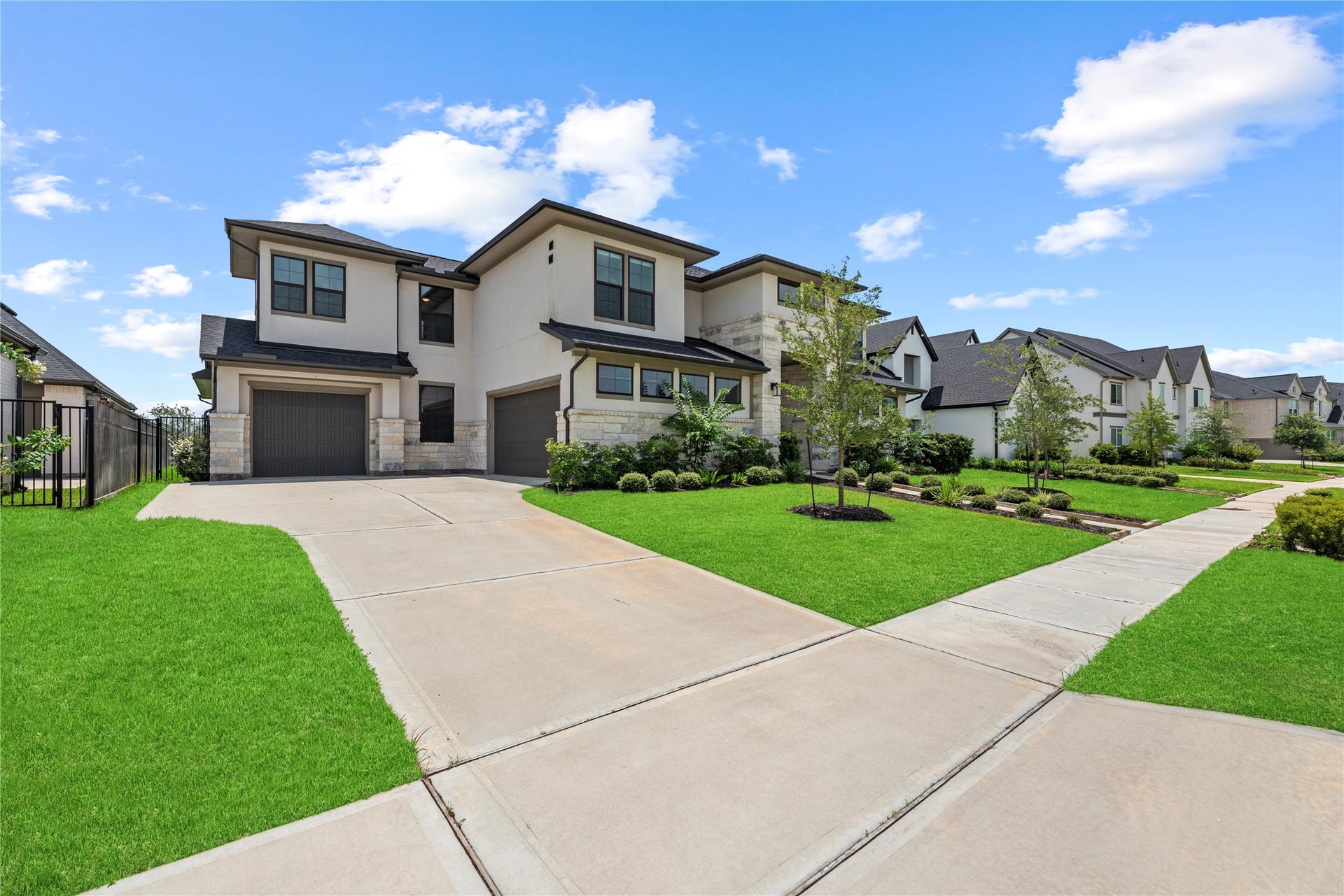 10314 Forest Lake Drive, Missouri City, TX 77459 Wide side angle showing off the expansive concrete driveway, multi-car garage space, stone and stucco exterior, and charming neighborhood streetscape.