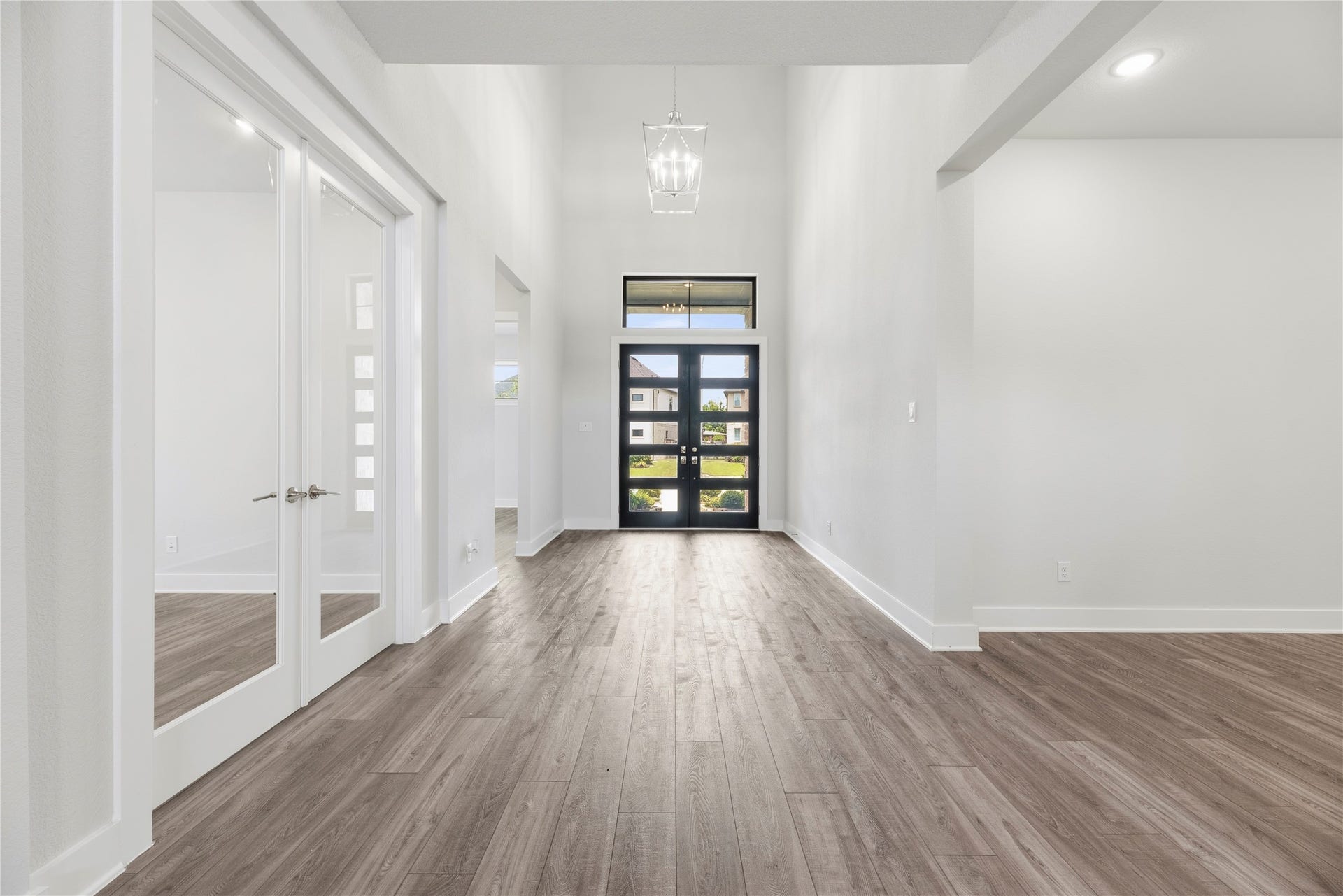 10314 Forest Lake Drive, Missouri City, TX 77459 Wide, light-filled foyer featuring double glass front doors, high ceilings with a classic statement pendant light, and French-door entry into the private study.