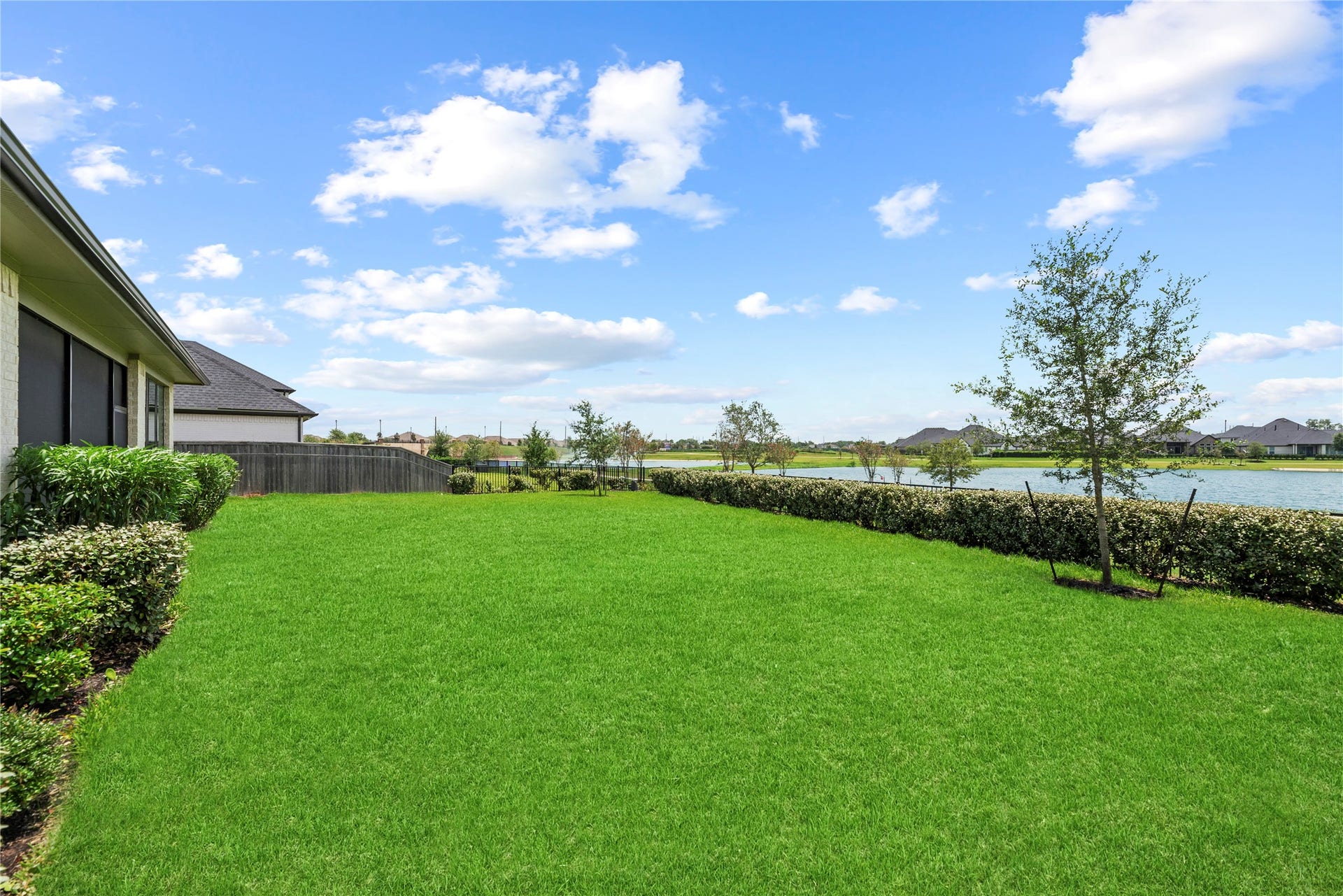10314 Forest Lake Drive, Missouri City, TX 77459 Generous green yard bordered by tailored hedges with direct views out over the neighborhood lake and community green space.