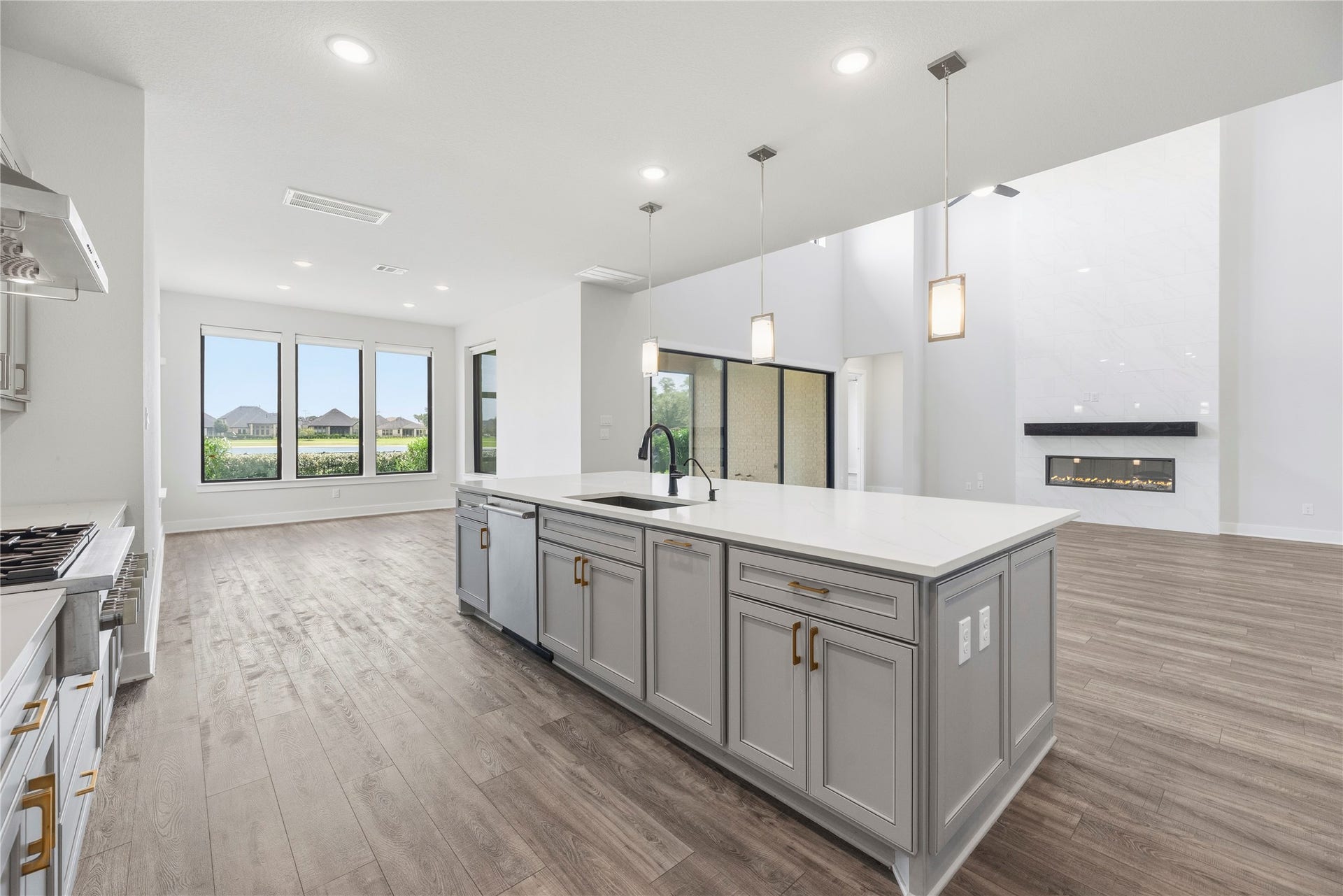 10314 Forest Lake Drive, Missouri City, TX 77459 Functional view from behind the kitchen island featuring an undermount stainless steel sink, built-in dishwasher, and direct sightlines to the fireplace and water-view windows.