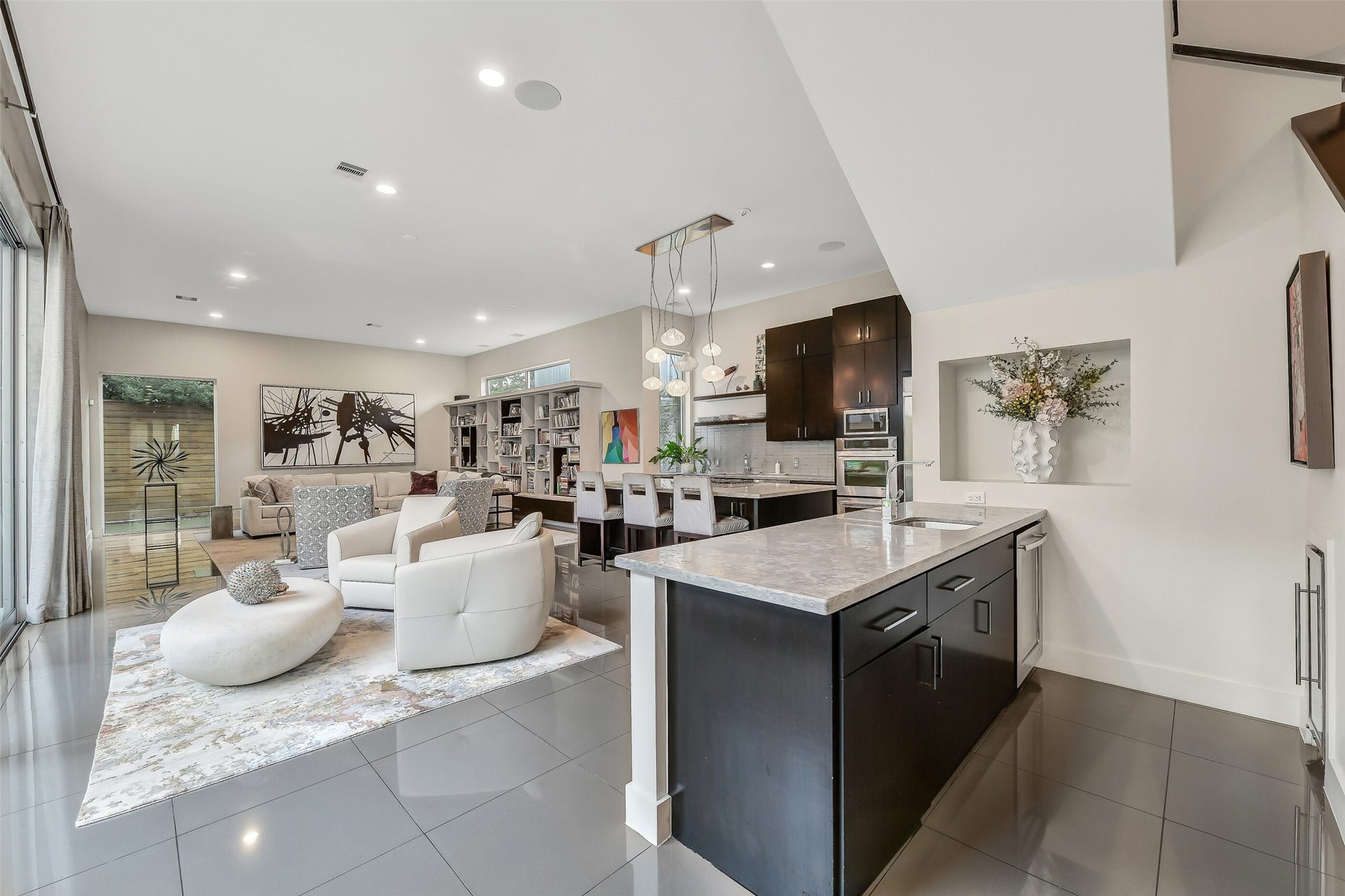 2302 Persa Street, Houston, TX 77019 Polished flooring and vaulted architectural angles set the stage for hospitility and entertaining in mind. A bar area or serving island, offering clear sightlines across the entire family area and out toward the private courtyard.