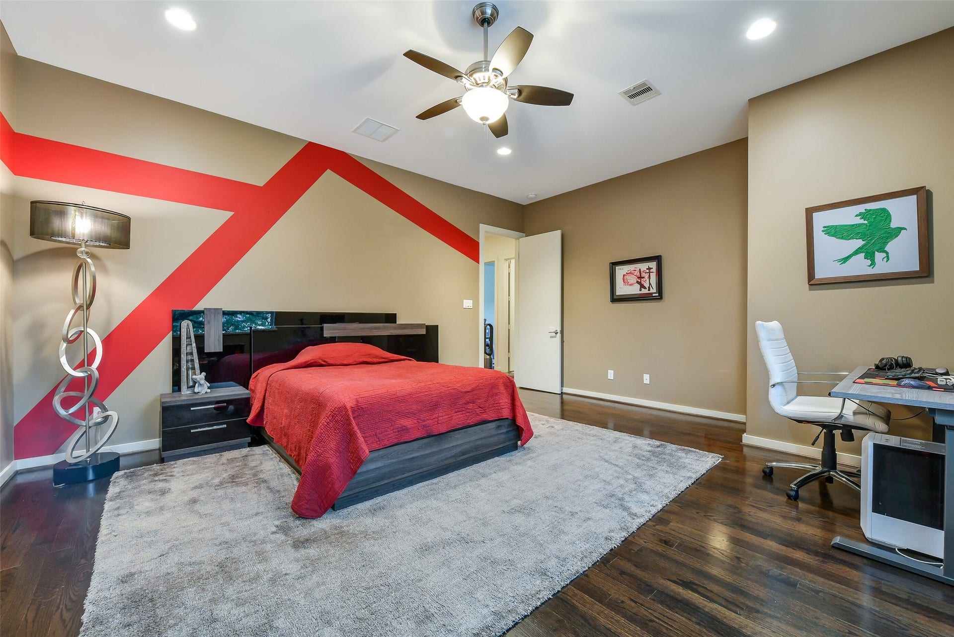 2302 Persa Street, Houston, TX 77019 The spacious secondary suite offers a generous layout featuring rich hardwood floors, neutral walls with bold accent geometric detailing, and direct access to its own private ensuite bathroom.