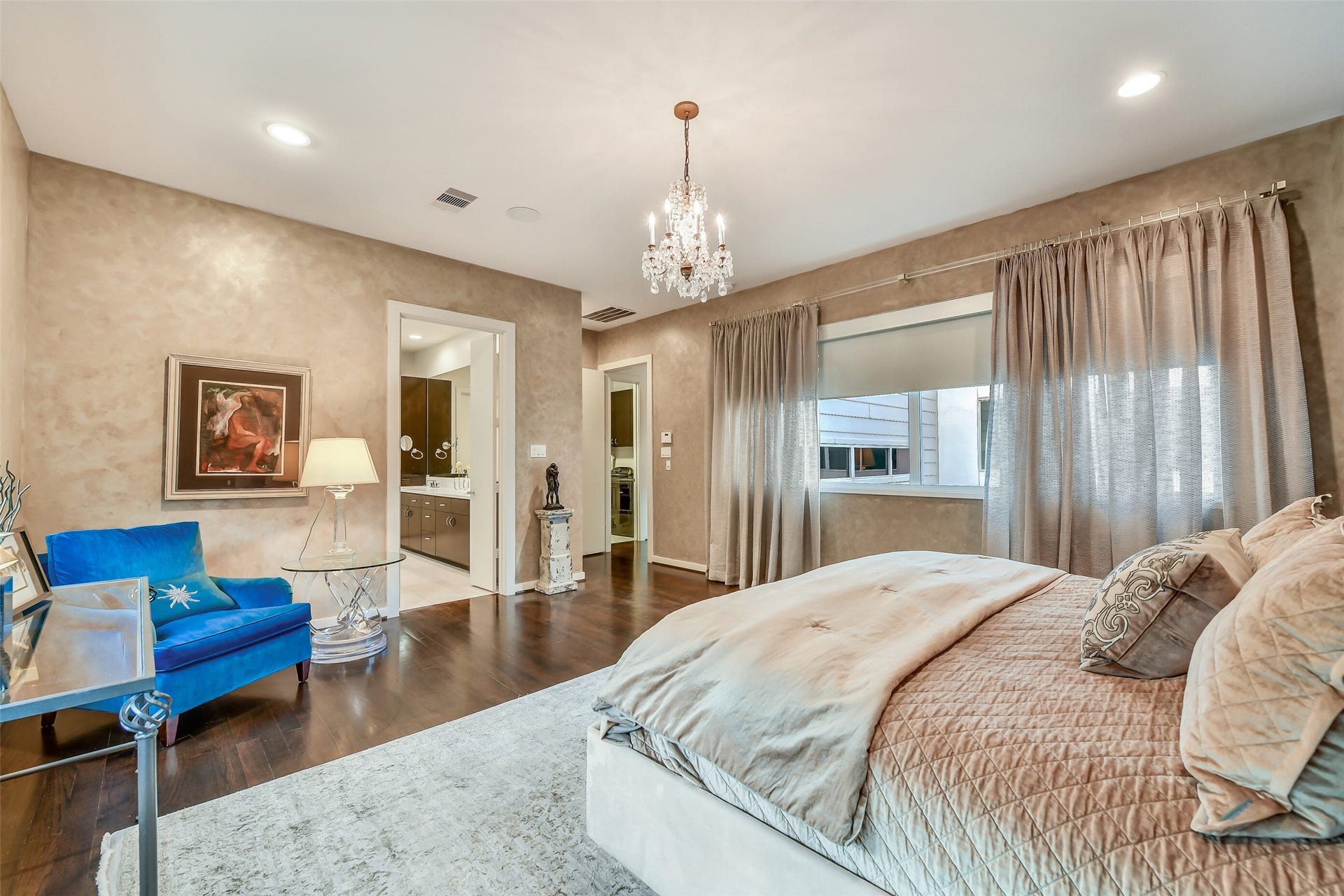 2302 Persa Street, Houston, TX 77019 Designed for ultimate comfort, this primary suite features warm neutral walls, rich hardwood flooring, and expansive windows framed by custom drapery and integrated shades.