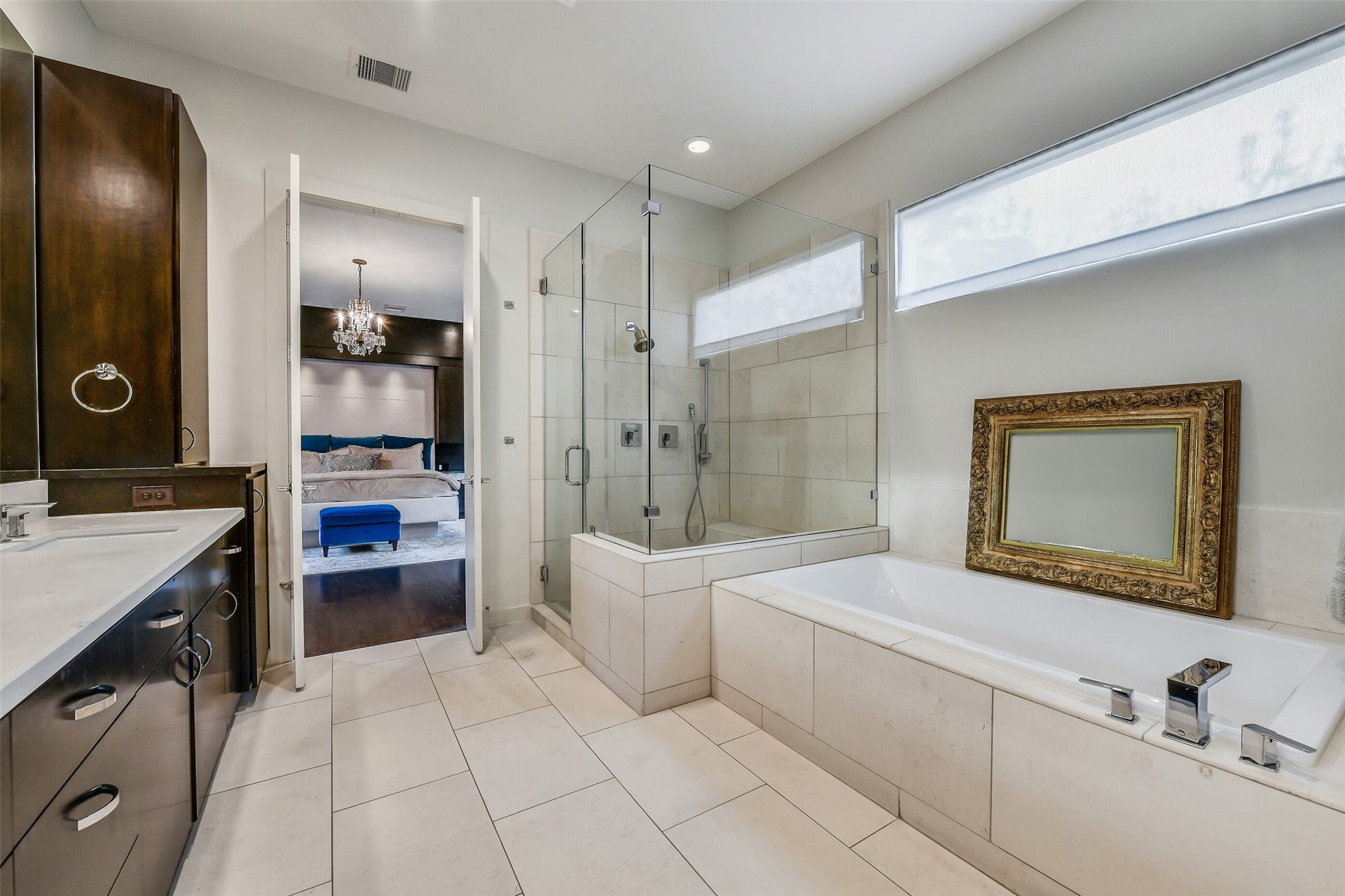 2302 Persa Street, Houston, TX 77019 Designed as a private oasis, this primary bathroom features a deep drop-in soaking tub, a frameless glass-enclosed shower, dual dark-wood vanities, and high transom windows that let in soft natural light while maintaining complete privacy.