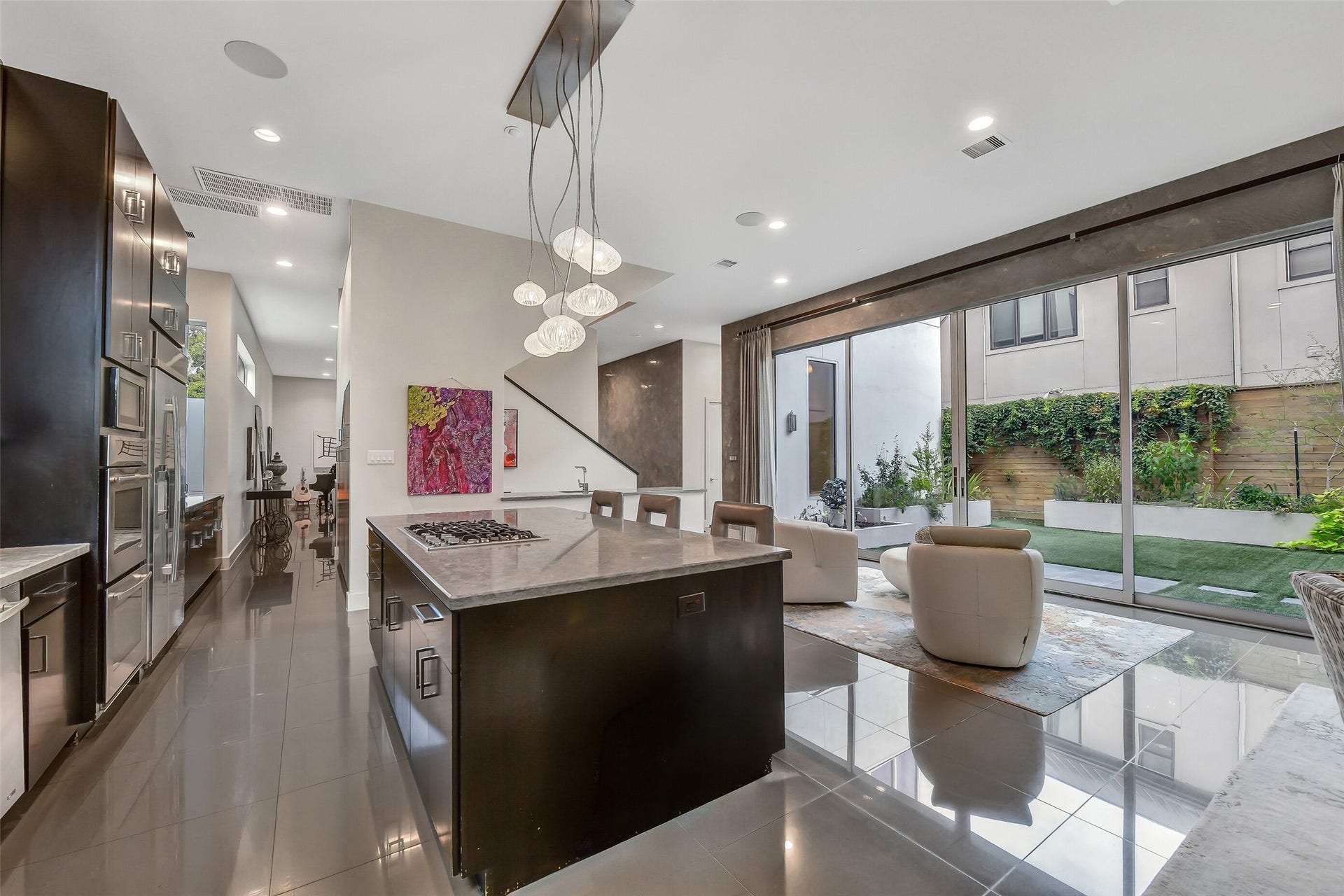 2302 Persa Street, Houston, TX 77019 Designed for effortless hosting, this light-filled kitchen features premium metallic finishes, a full-length breakfast bar, and direct visual connections to adjacent living and outdoor courtyard spaces.
