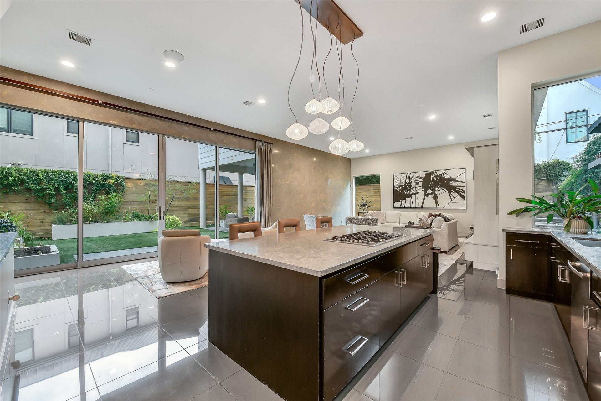 2302 Persa Street, Houston, TX 77019 The expansive views highlight the home's open concept design, effortlessly connecting the gourmet kitchen, casual dining, and main family living areas into one light-filled sanctuary. Massive glass sliding doors open directly onto the private side patio and outdoor living areas create the perfect setting for family gatherings or entertaining.