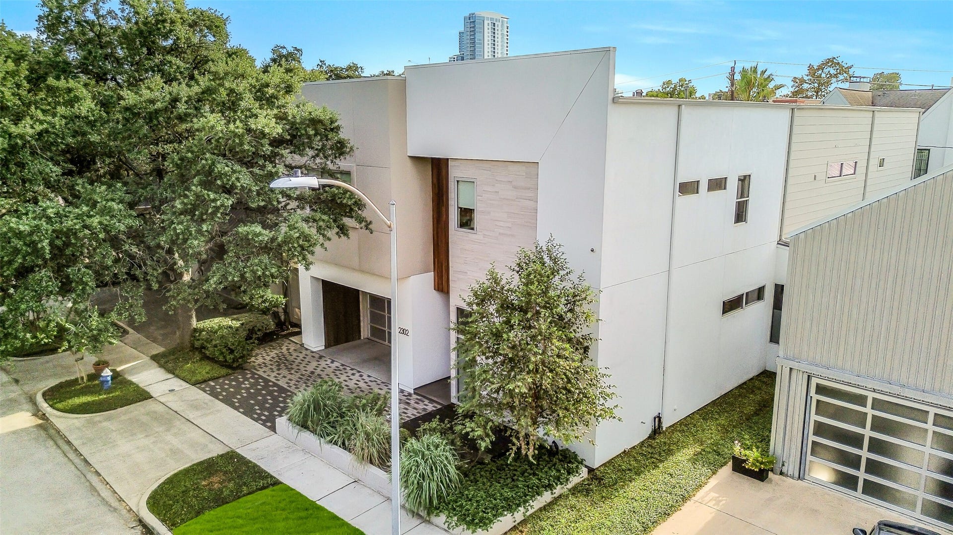 2302 Persa Street, Houston, TX 77019 Defined by sharp geometric lines, smooth stucco, and rich natural wood accents, this contemporary two-story home makes an immediate architectural statement, beautifully framed by a sprawling mature live oak tree.