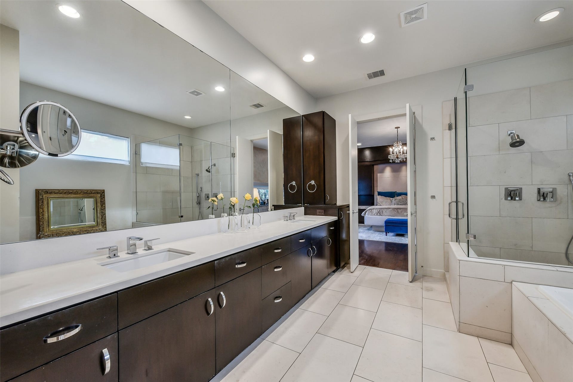 2302 Persa Street, Houston, TX 77019 This luxurious primary bath features dual dark-wood vanities, a deep soaking tub, and a frameless glass shower illuminated by soft natural light.
