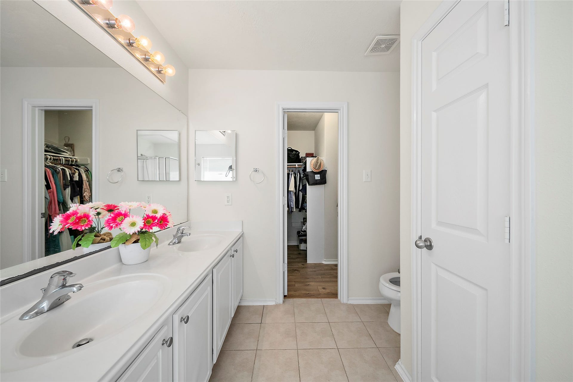 Bright and airy room with large windows, wood flooring, and neutral walls. Features include a ceiling fan, built-in shelving for books or decor, and a cozy seating area. Ideal for a family space or study.
