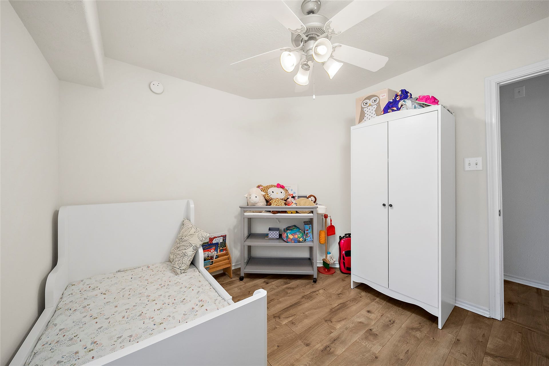 This open-concept living area features wood flooring, a modern kitchen with white cabinetry, and ample natural light. The space includes a cozy dining area, a ceiling fan, and a staircase leading to the upper floor, offering a welcoming and functional layout.