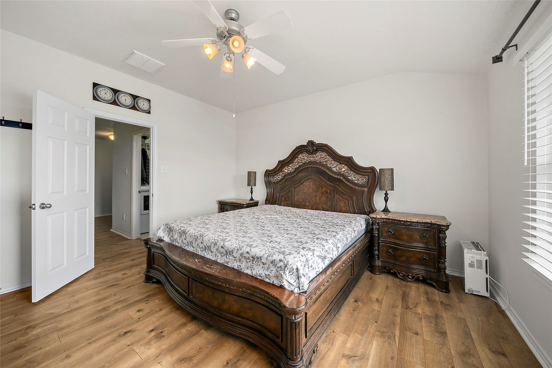 Spacious primary bedroom featuring elegant hardwood floors, abundant natural light, and a stylish ceiling fan for comfort.